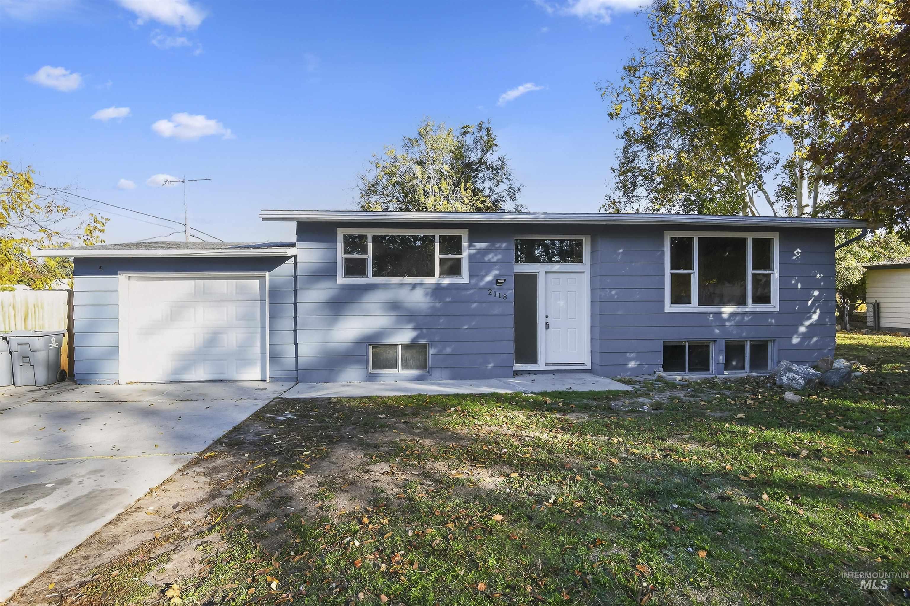 Split foyer home with a patio area, driveway, a front yard, and an attached garage