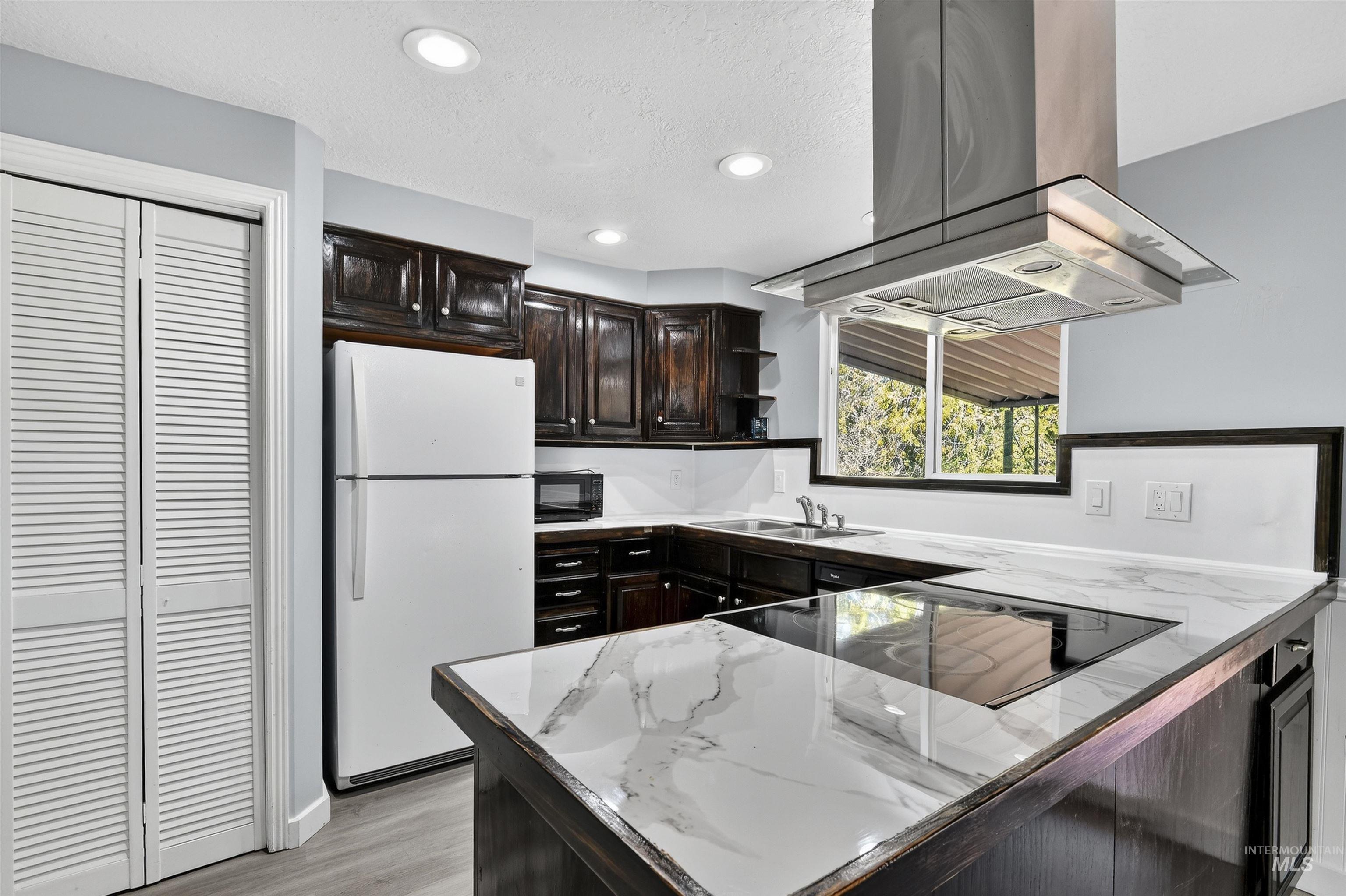 Kitchen featuring open shelves, black appliances, island exhaust hood, recessed lighting, and light wood-style floors
