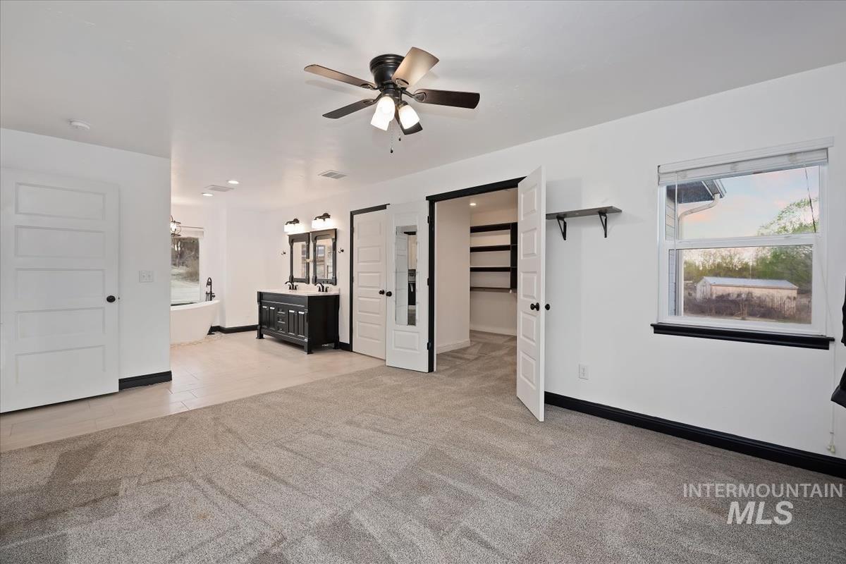 Unfurnished living room with light colored carpet, ceiling fan, and light tile patterned floors