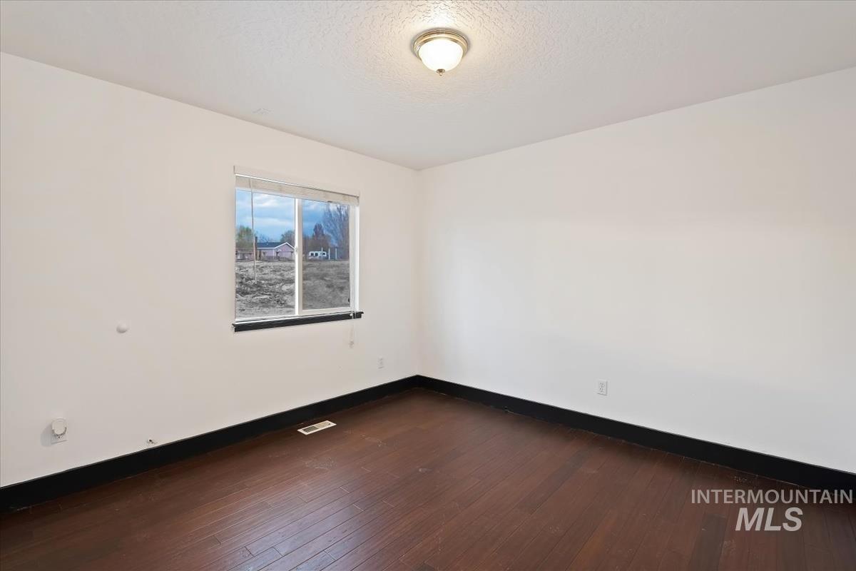Empty room featuring dark wood-style flooring and a textured ceiling