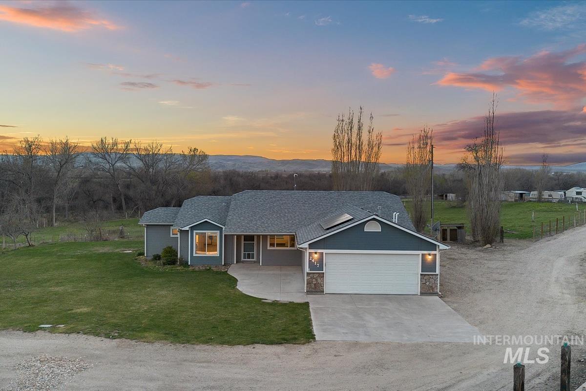 View of front of home featuring driveway, a yard, stone siding, a garage, and a porch