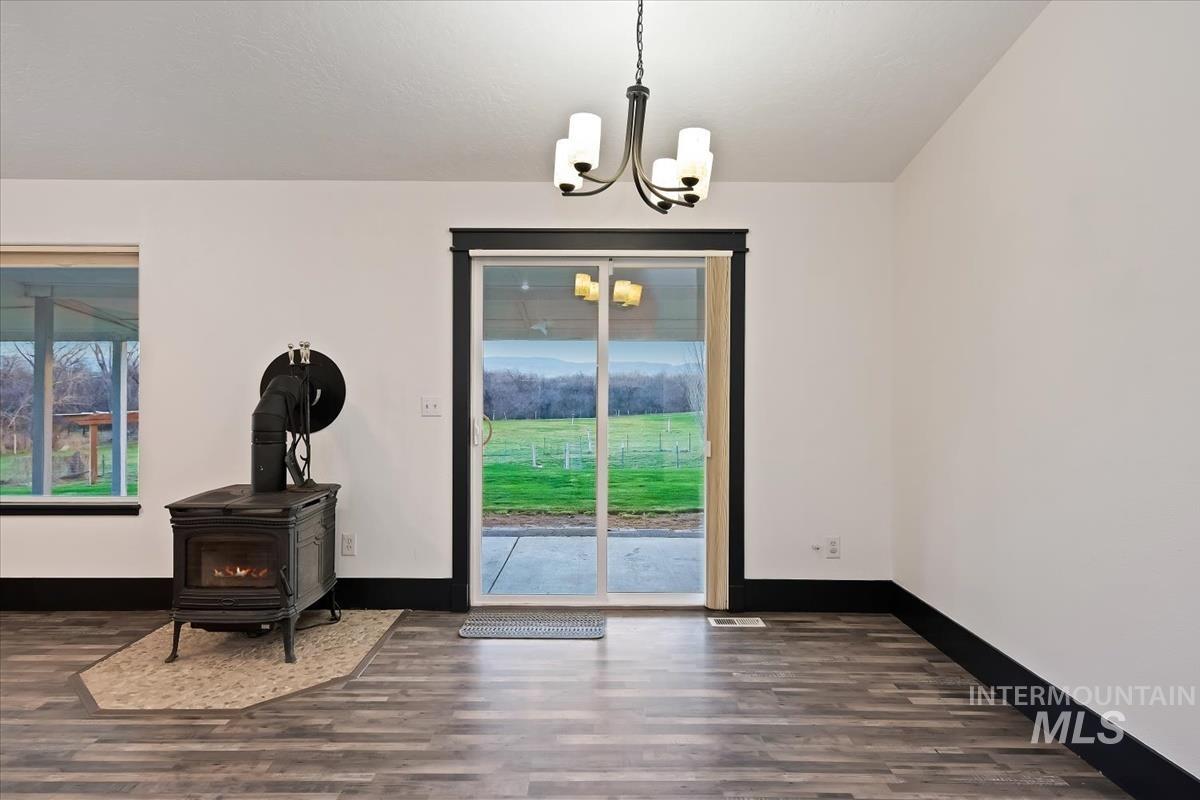 Dining room featuring a wood stove, dark wood-style flooring, and suspended lighting