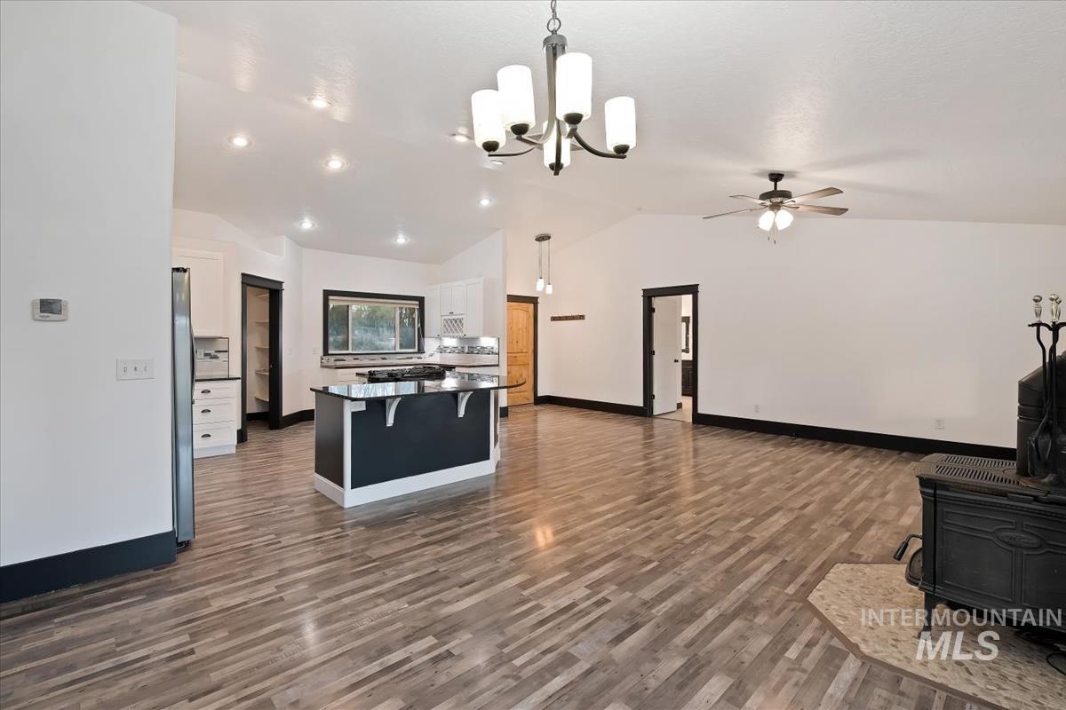 Kitchen featuring a kitchen island, a wood stove, open floor plan, white cabinets, and dark wood-style flooring
