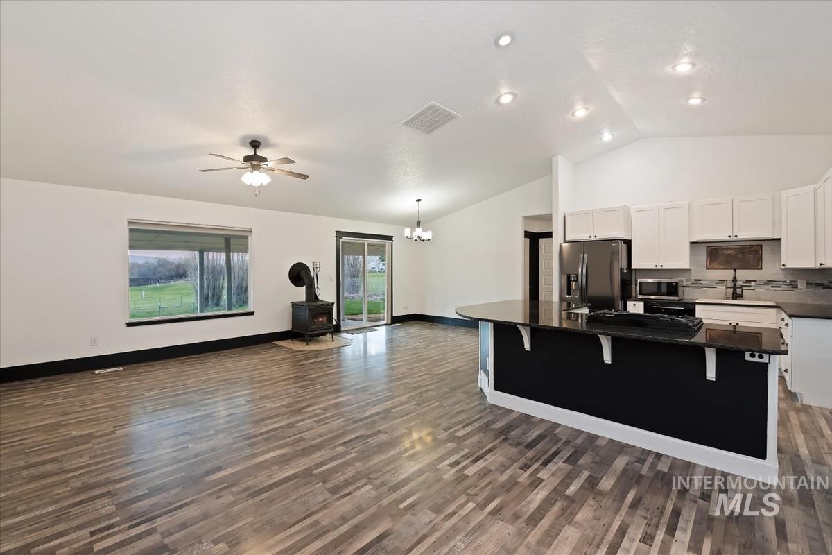 Kitchen featuring white cabinets, stainless steel appliances, a kitchen island, a wood stove, and suspended lighting