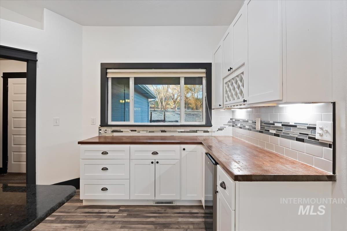 Kitchen featuring wooden counters, tasteful backsplash, white cabinets, and dark wood finished floors