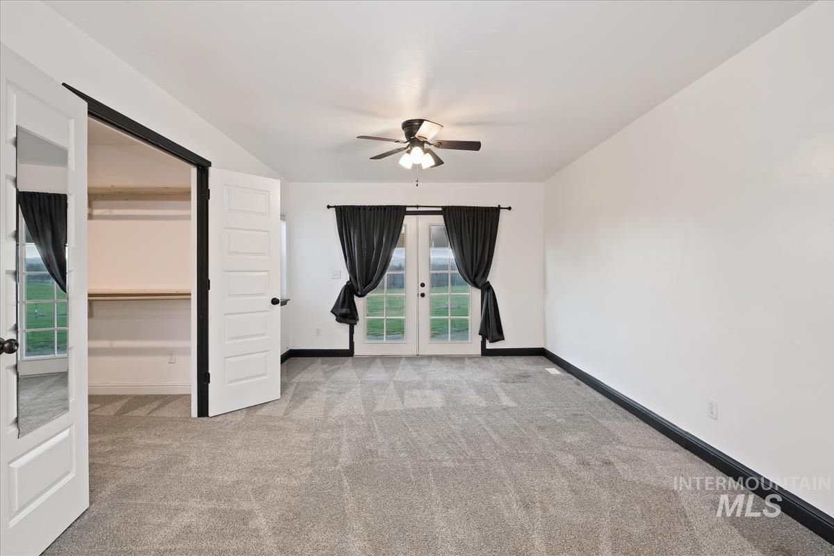 Unfurnished bedroom featuring french doors, light colored carpet, access to outside, a ceiling fan, and a spacious closet