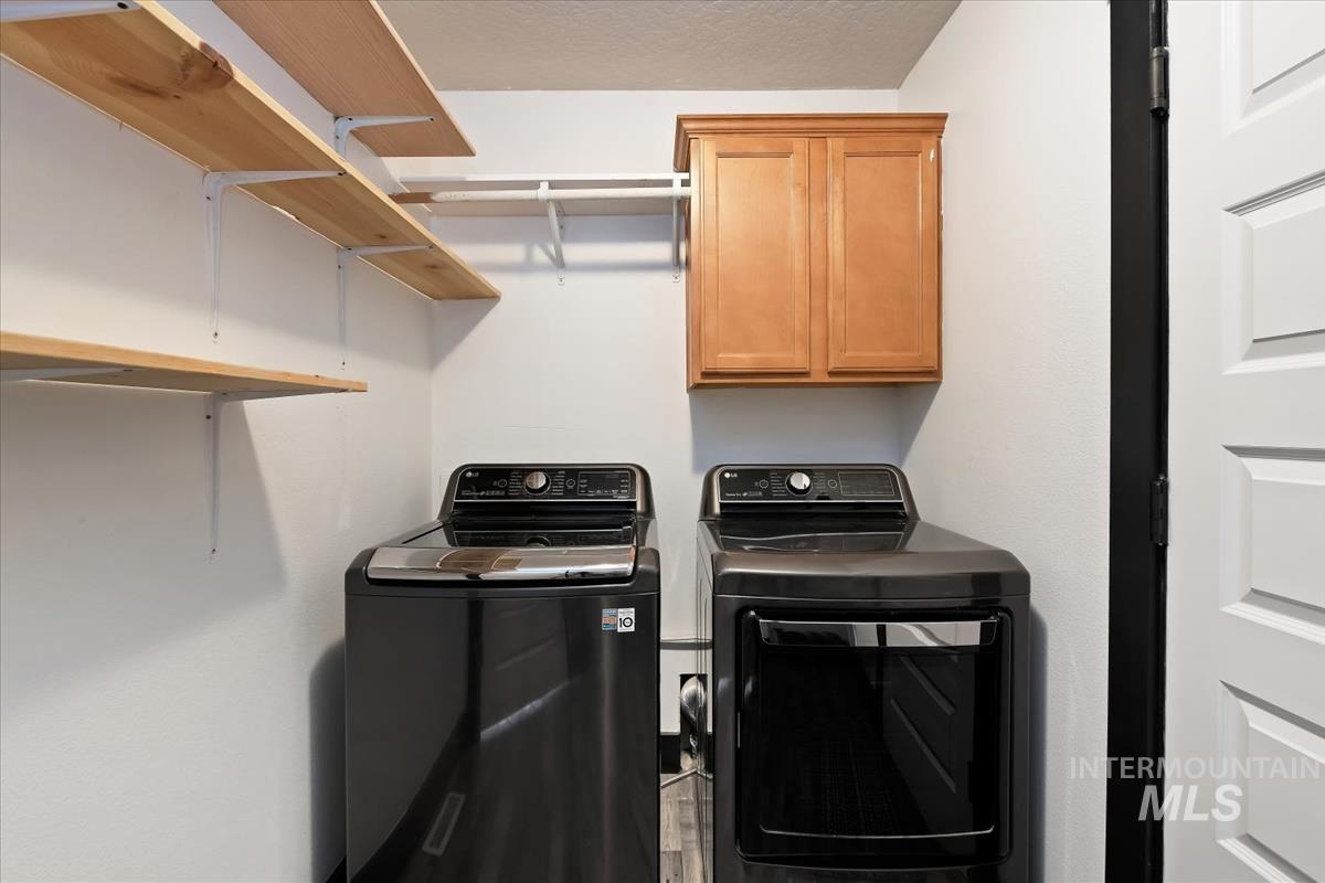 Laundry room featuring cabinet space, washing machine and clothes dryer, and a textured ceiling
