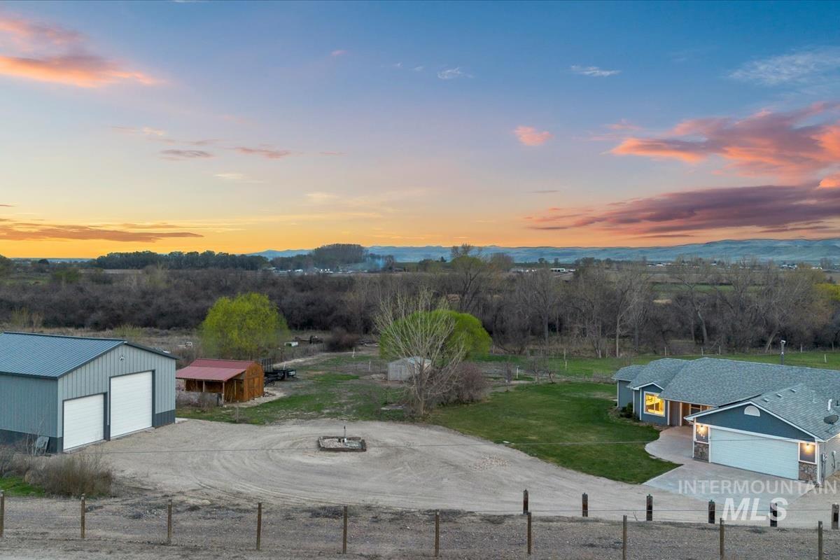 Yard at dusk with an outbuilding, a detached garage, a rural view, and dirt driveway