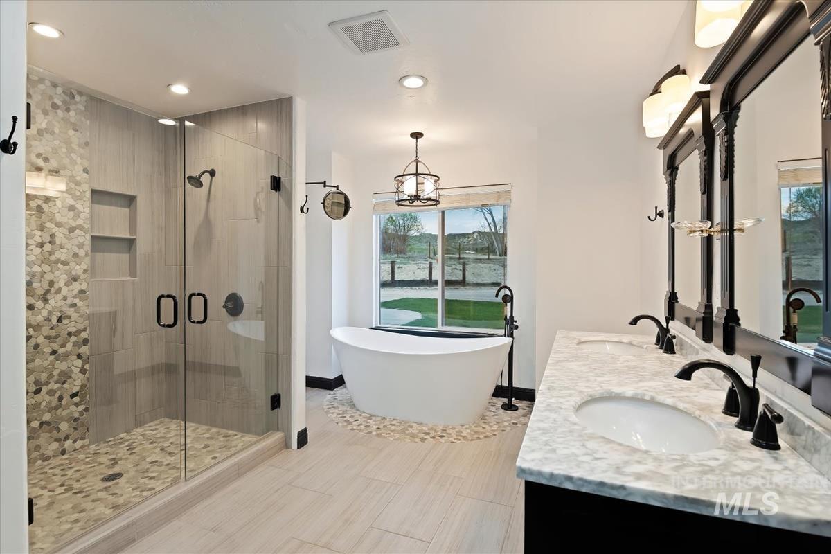 Bathroom with a stall shower, double vanity, a freestanding tub, and recessed lighting