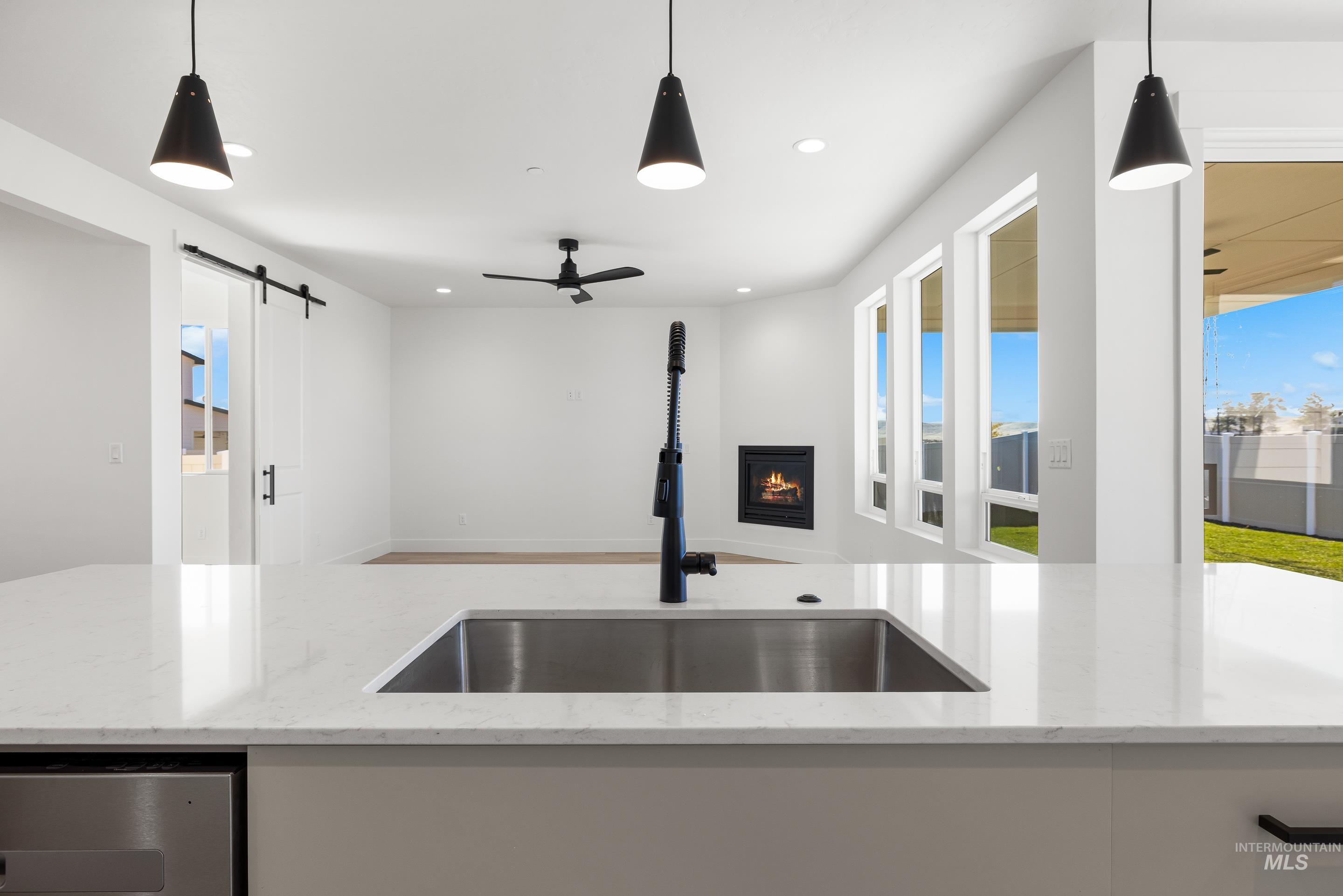 Kitchen with hanging light fixtures, open floor plan, light stone counters, recessed lighting, and a barn door