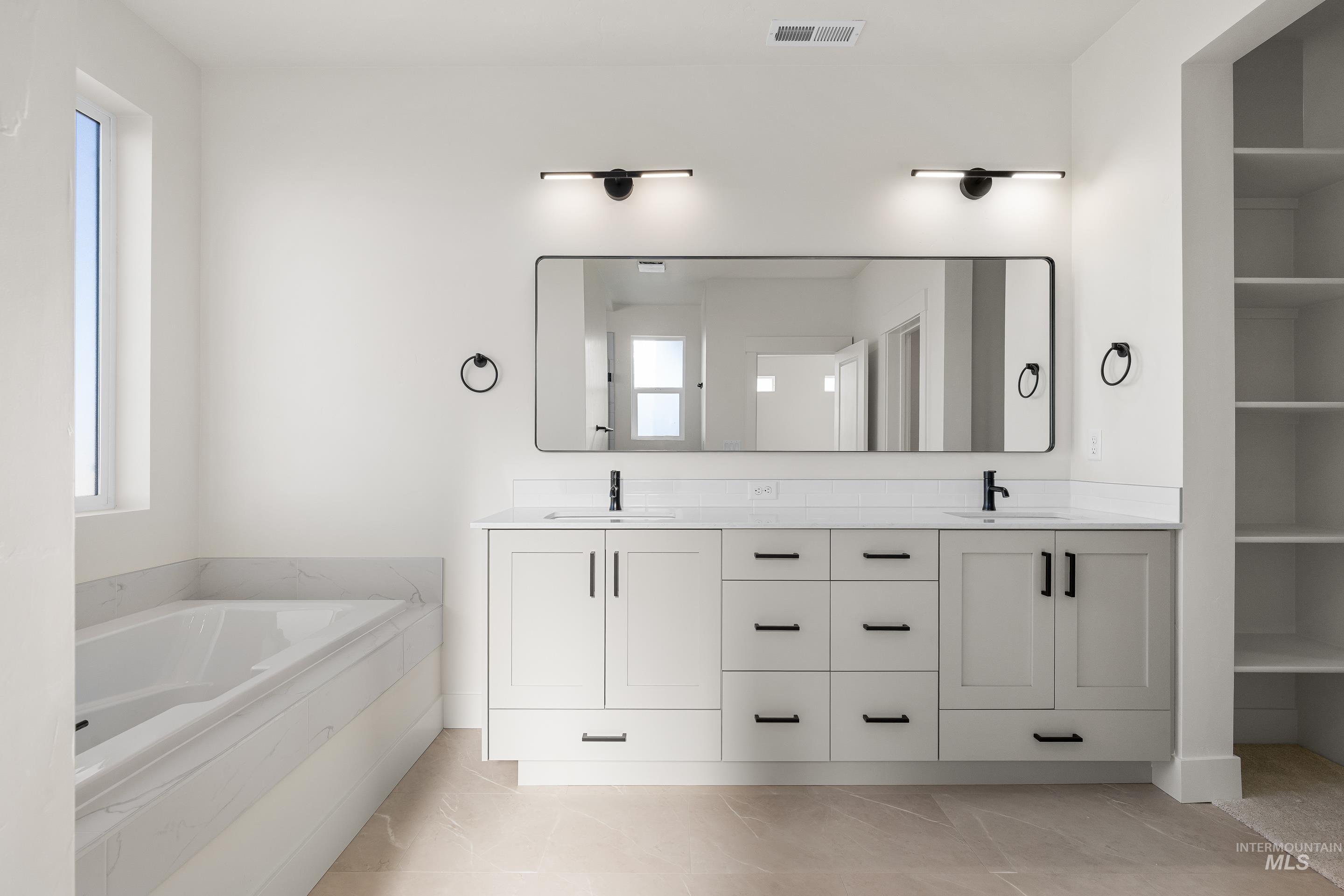 Bathroom featuring double vanity, a bath, and light tile patterned floors