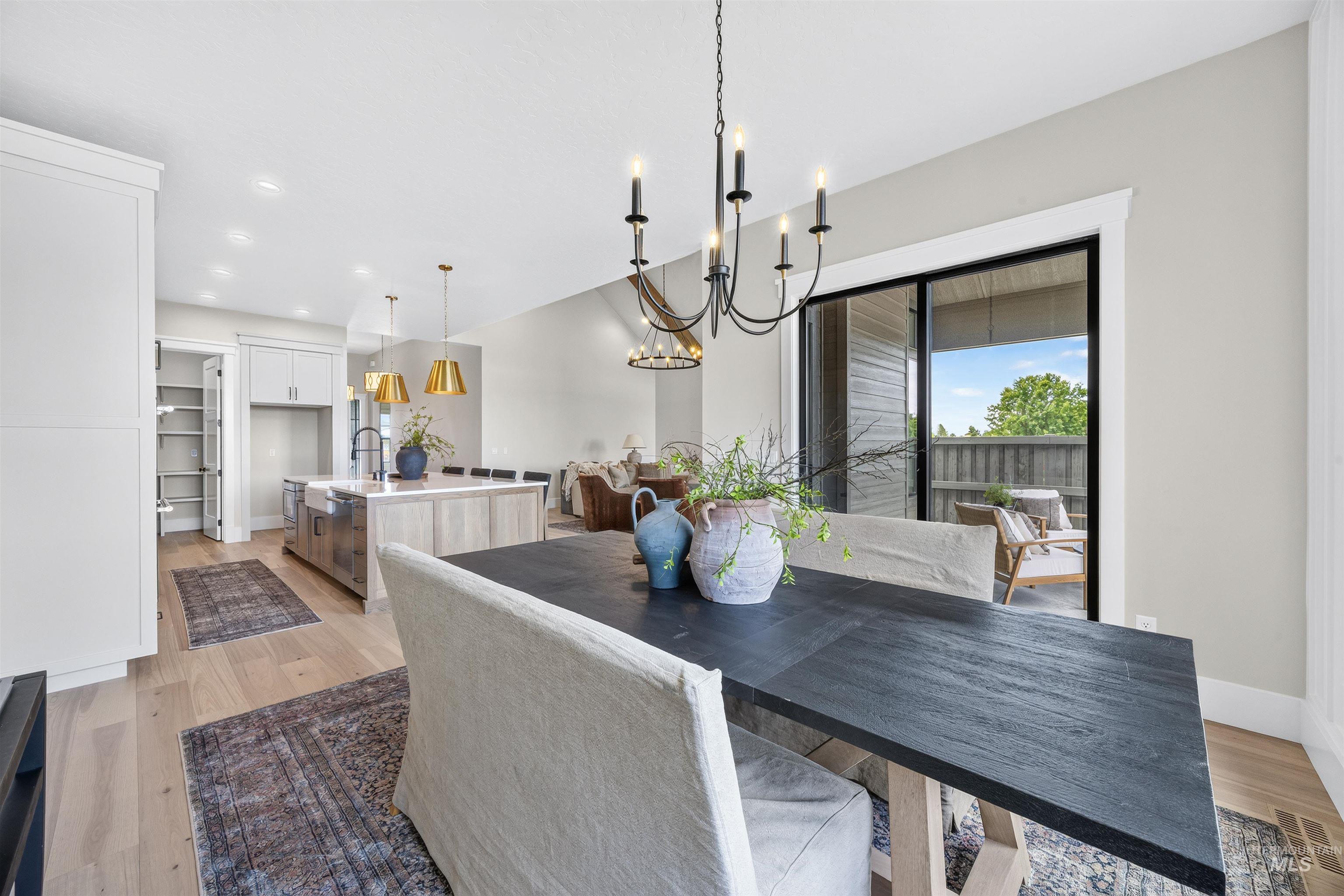 Dining area featuring a dark-finish table and chandelier, light wood-finish flooring, and a sliding glass door leading to an outdoor space