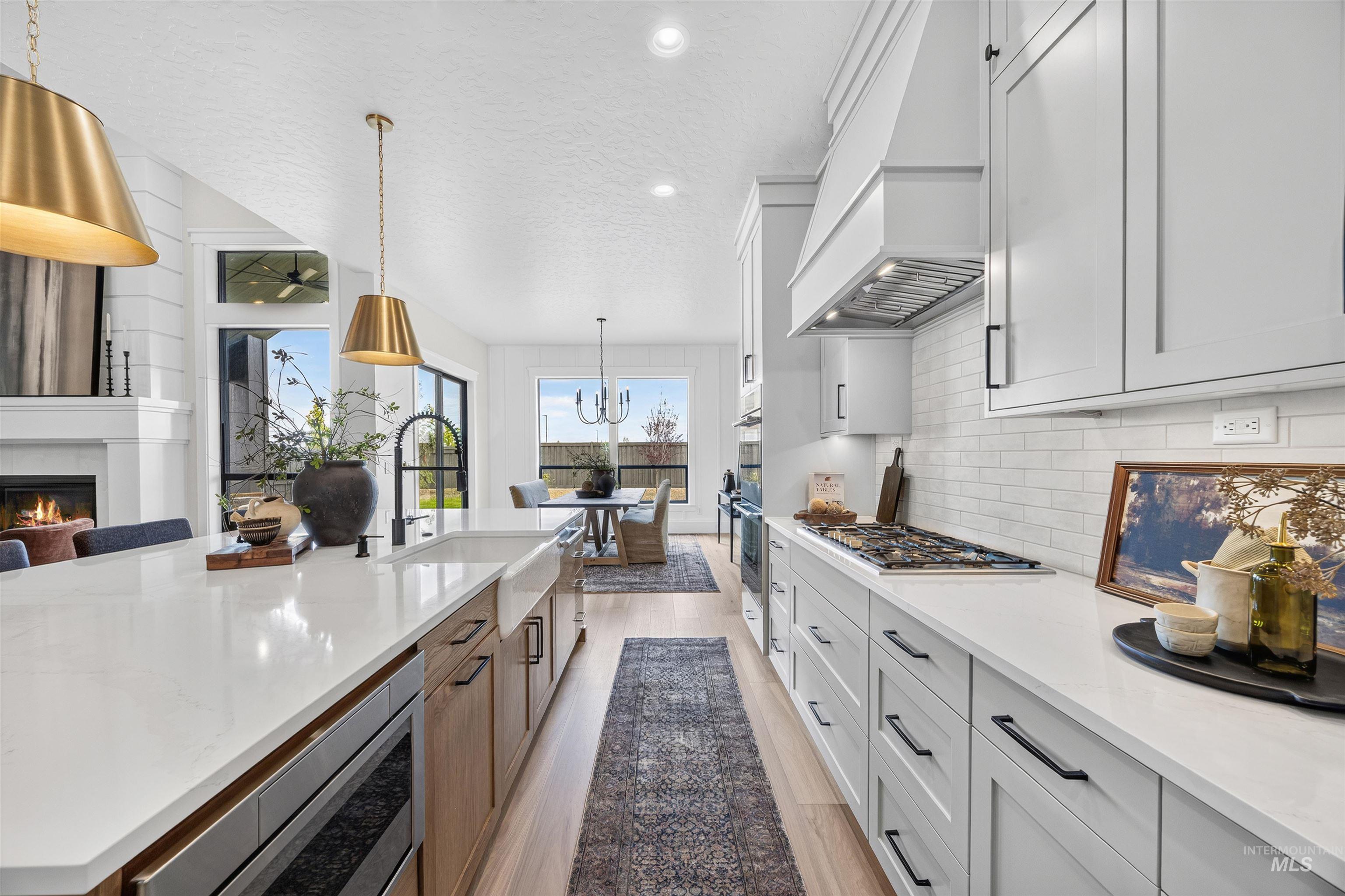 Gourmet kitchen featuring a large island with white stone countertops, farmhouse sink, and brass pendant lighting