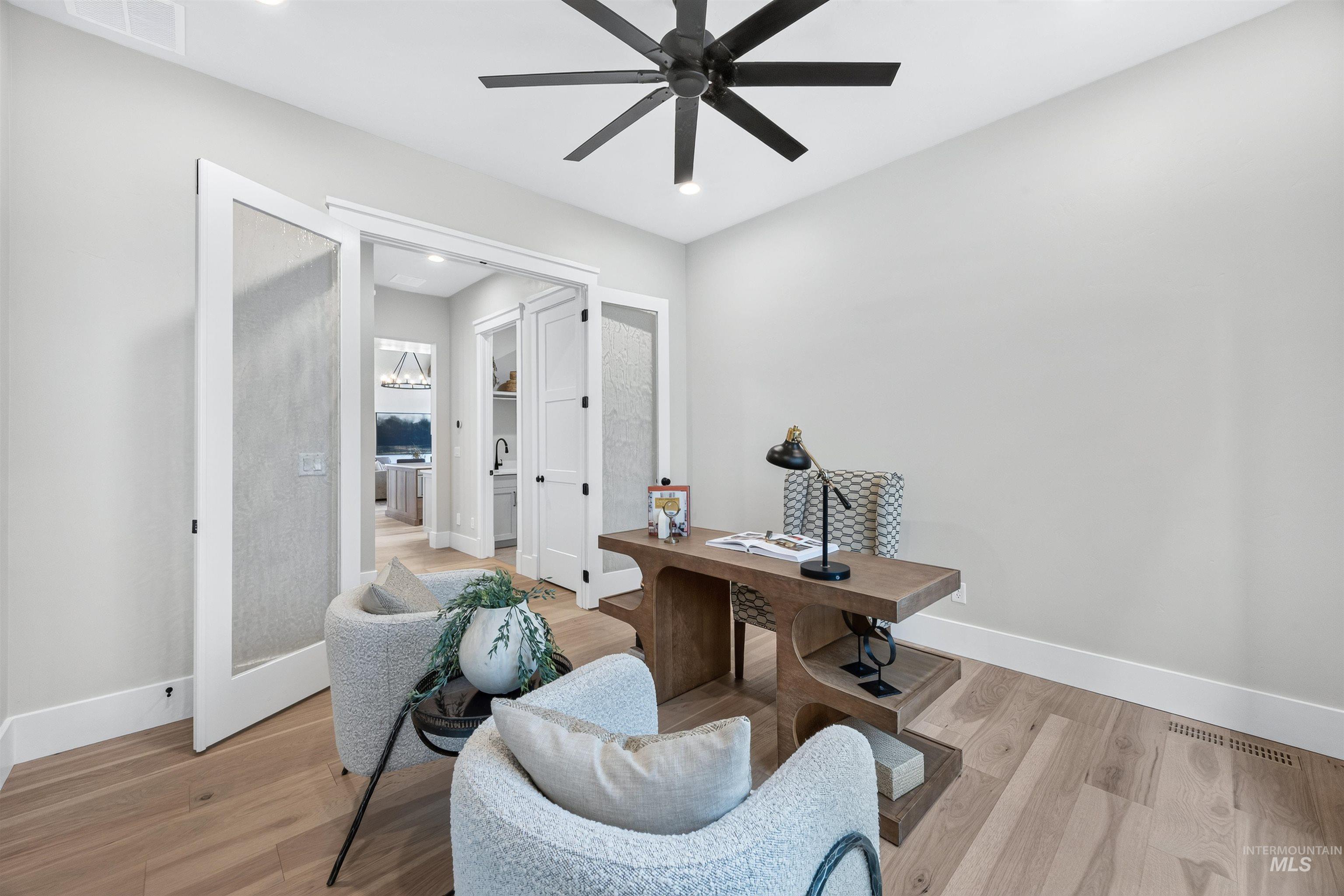 Dedicated room featuring wood-finish flooring, a modern black ceiling fan, recessed lighting, and white baseboards