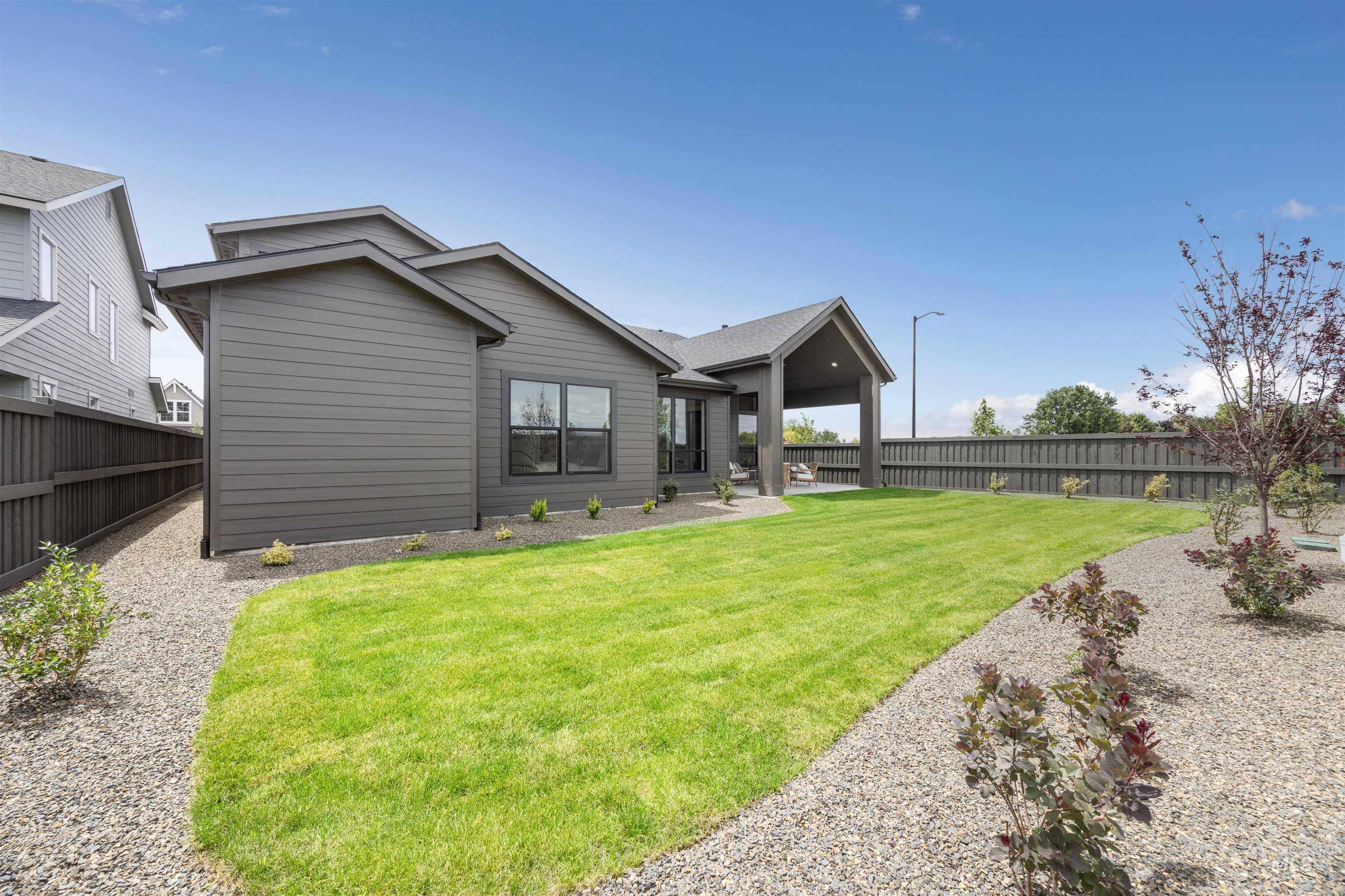 Expansive backyard featuring a manicured lawn, gravel landscaping, and mature foliage
