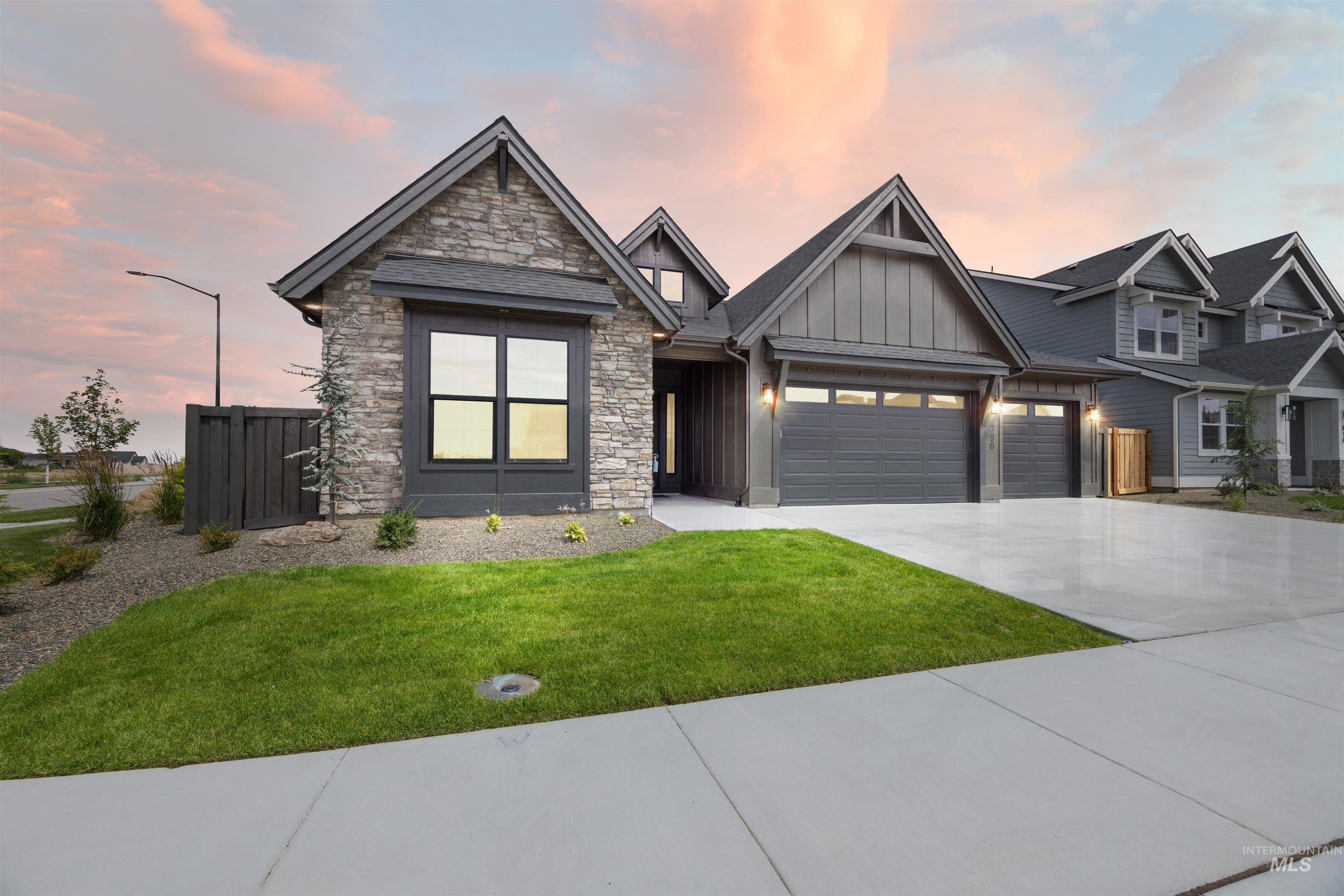 Contemporary residential exterior featuring stone and board-and-batten siding, a prominent gable roofline, and a three-car garage