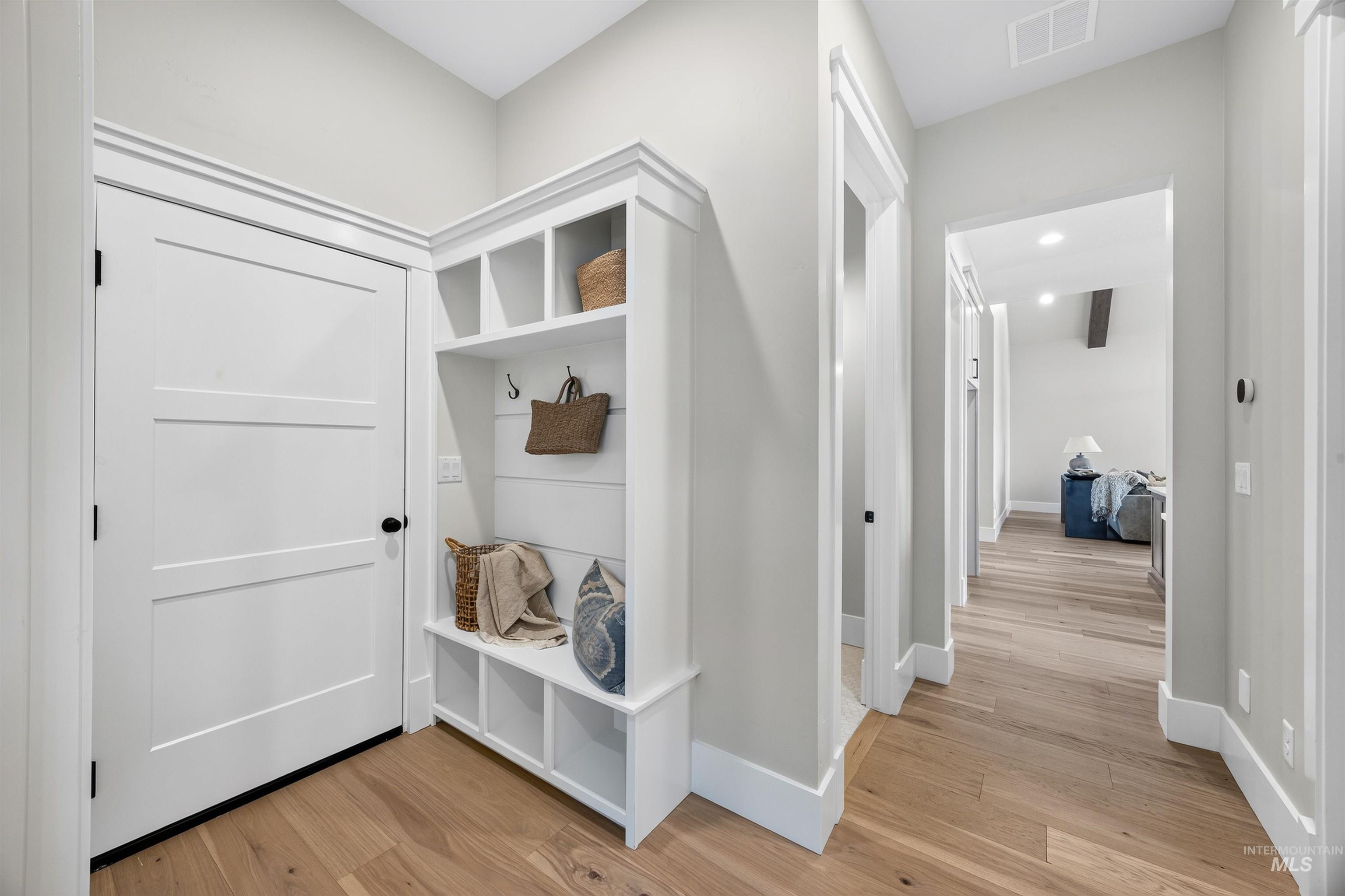 Entryway featuring built-in cabinetry with cubby storage, shiplap backing, and coat hooks