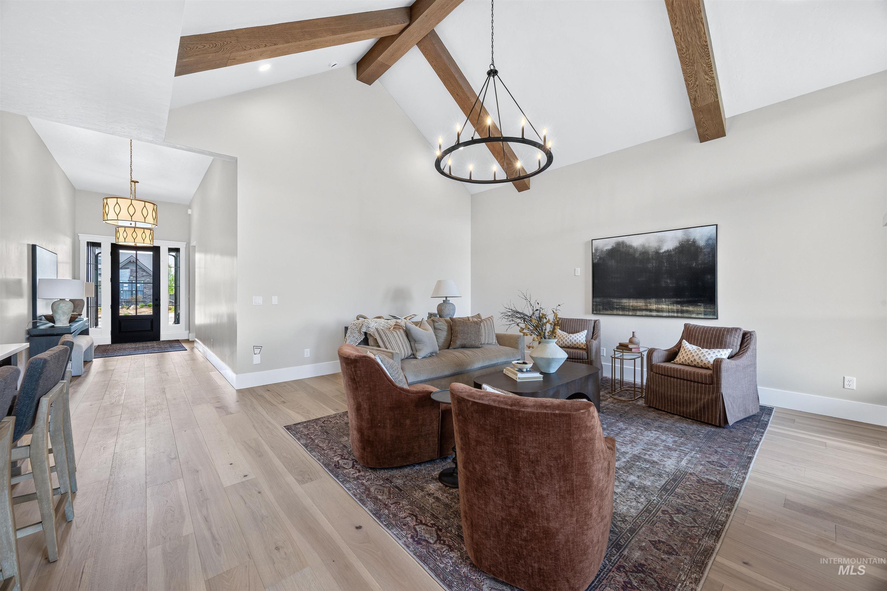 Vaulted ceilings with exposed wood beams, wood-finish flooring, and a large circular chandelier