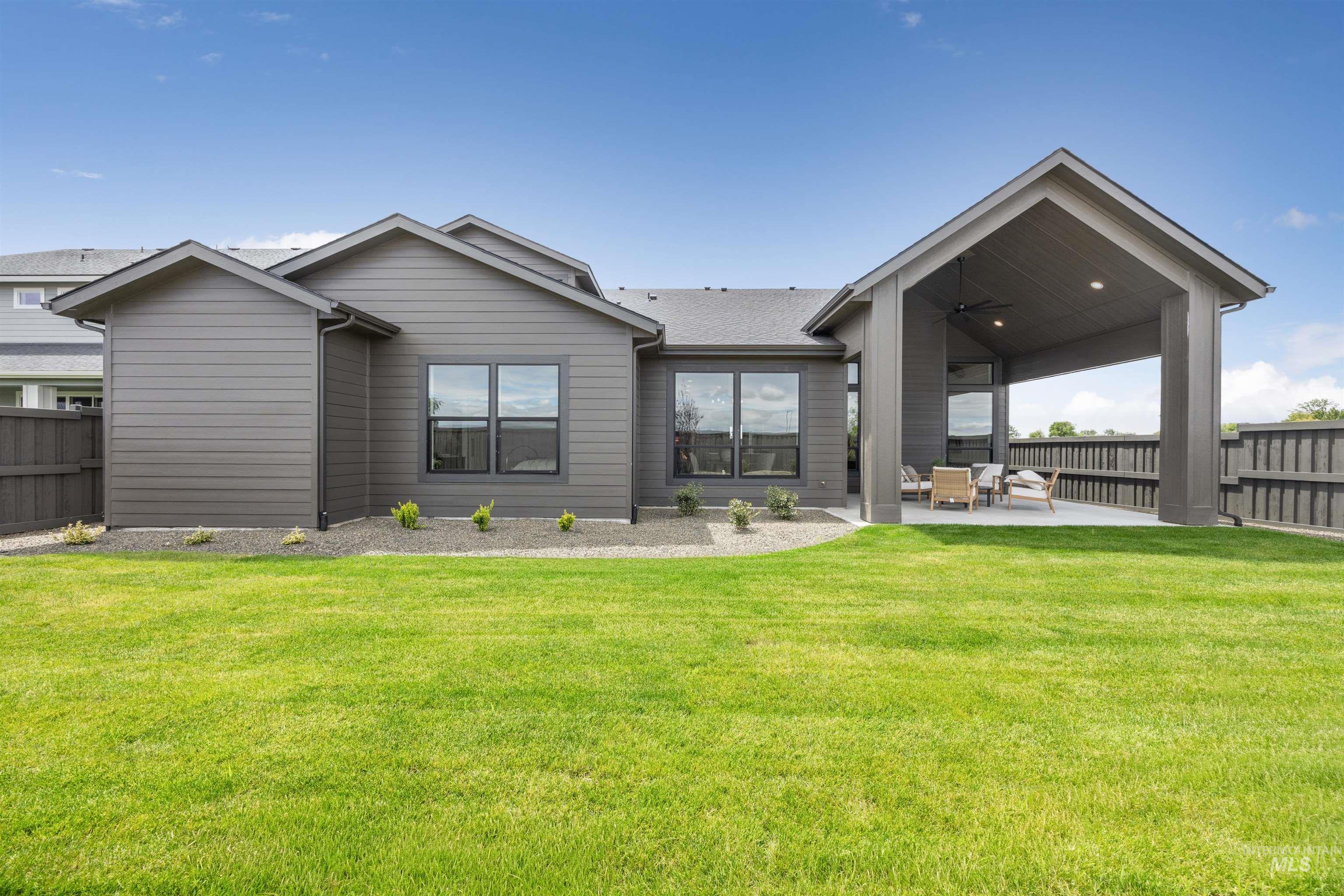Expansive backyard with a manicured lawn, a covered patio, and a privacy fence