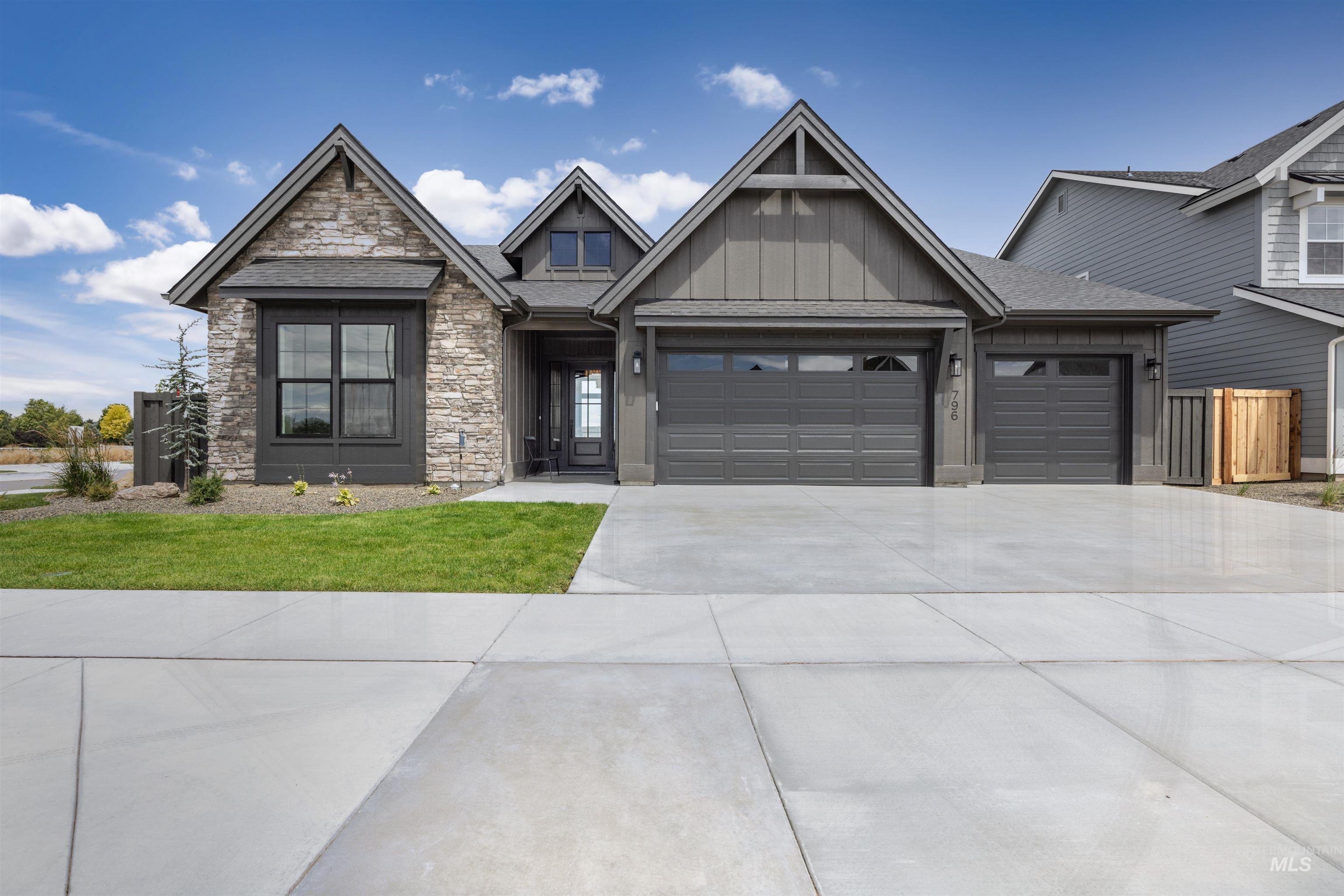 Modern craftsman-style exterior featuring stone accents, dark gray siding, and a multi-gabled roofline