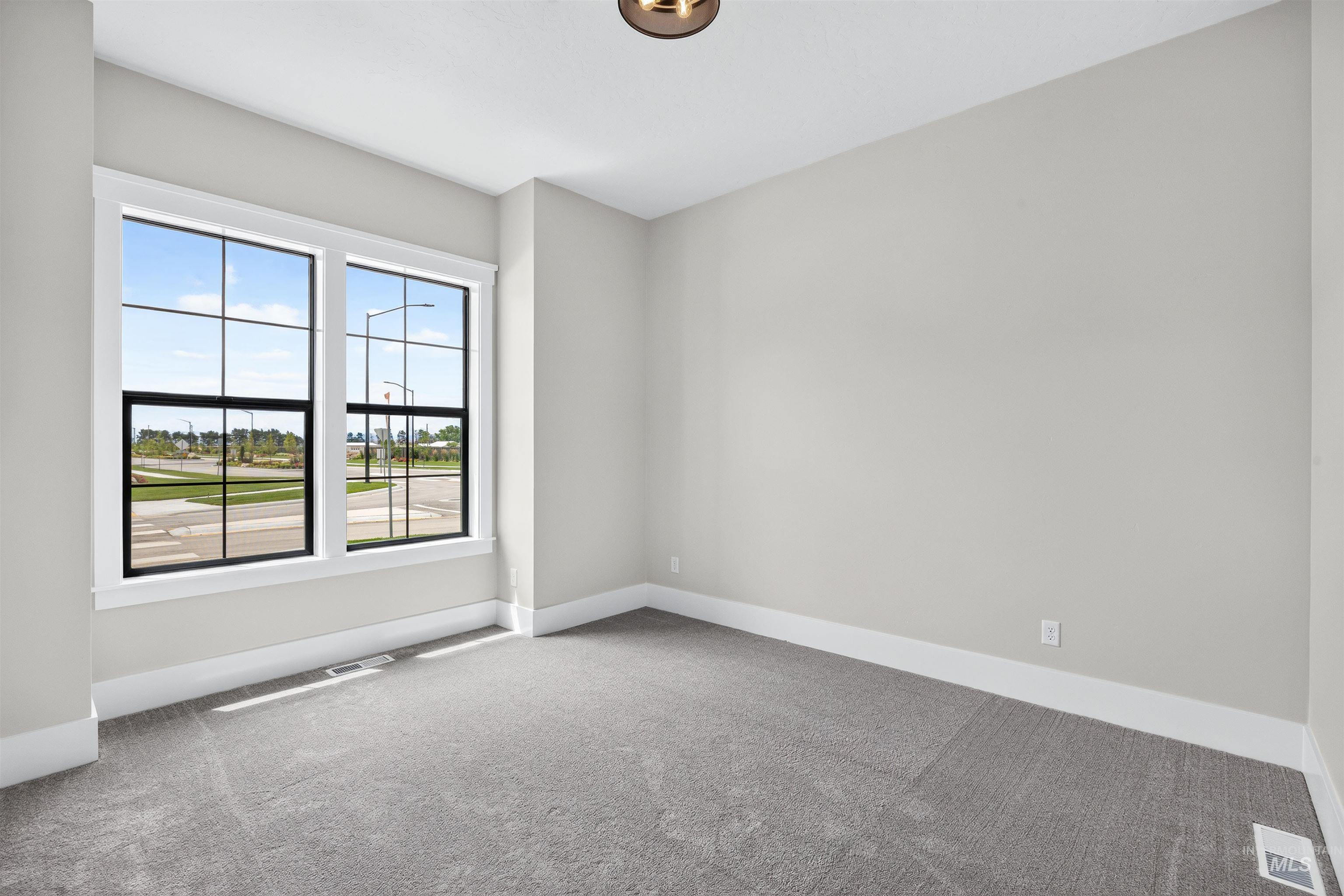Room featuring two large grid-pattern windows, light gray wall paint, and gray carpeting