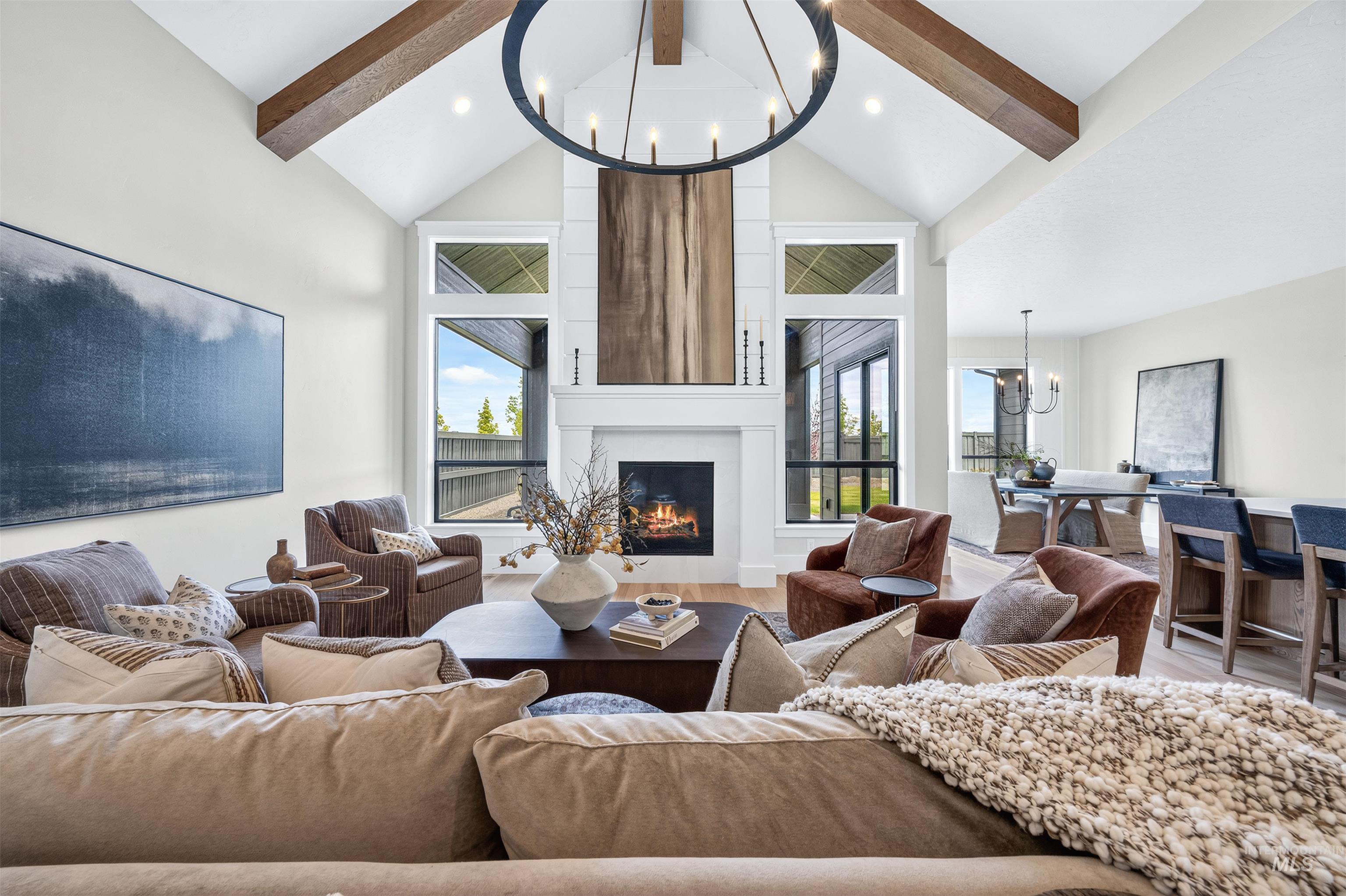 Vaulted living area featuring exposed wood beams and a large circular chandelier