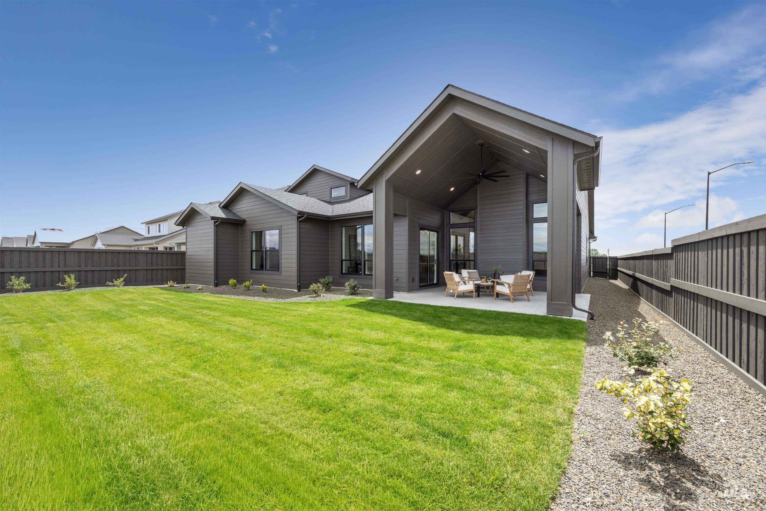 Expansive backyard featuring a manicured lawn, a covered patio, and a gravel-lined border