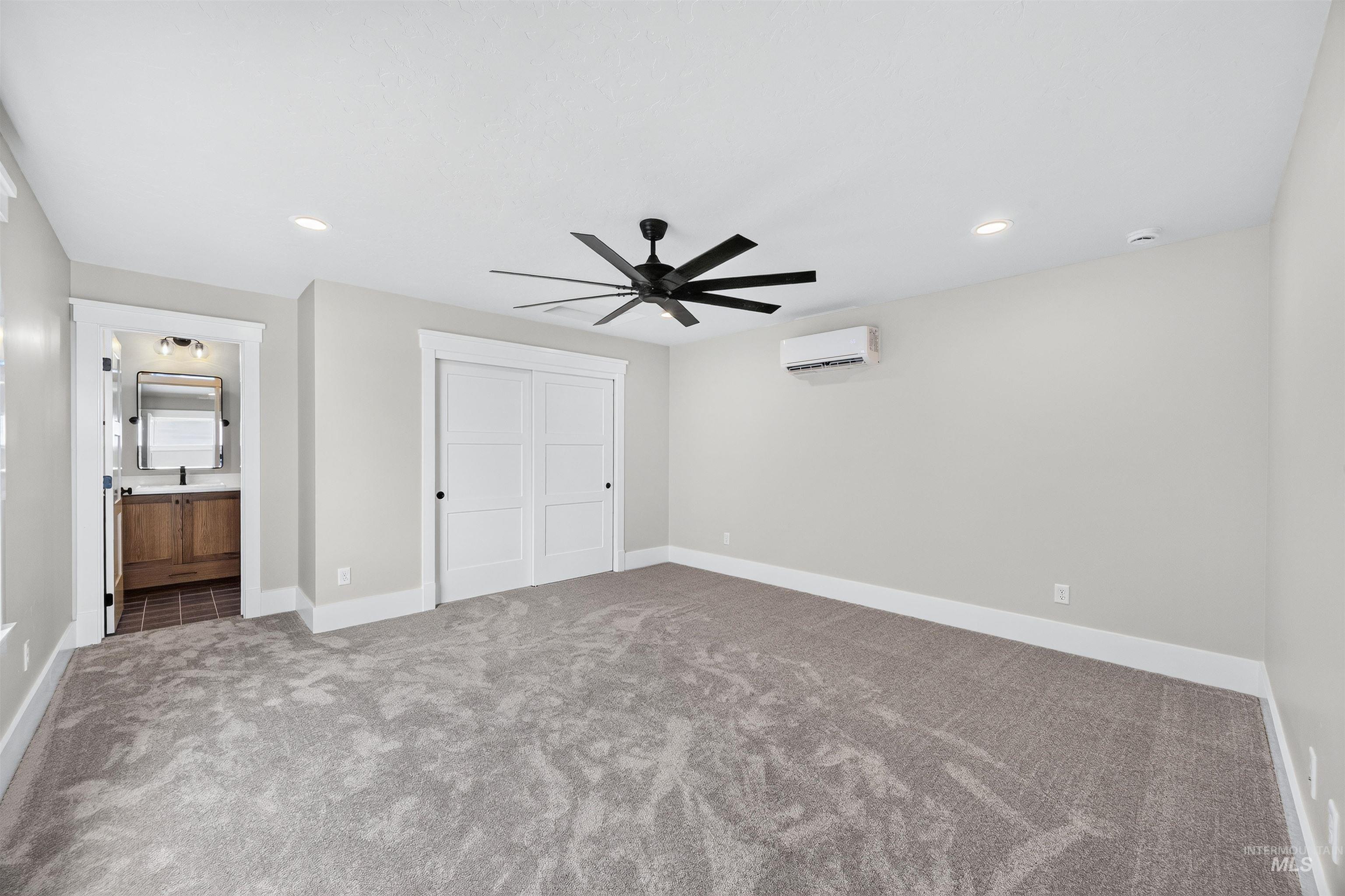 Carpeted room featuring a ceiling fan, recessed lighting, and a ductless mini-split system
