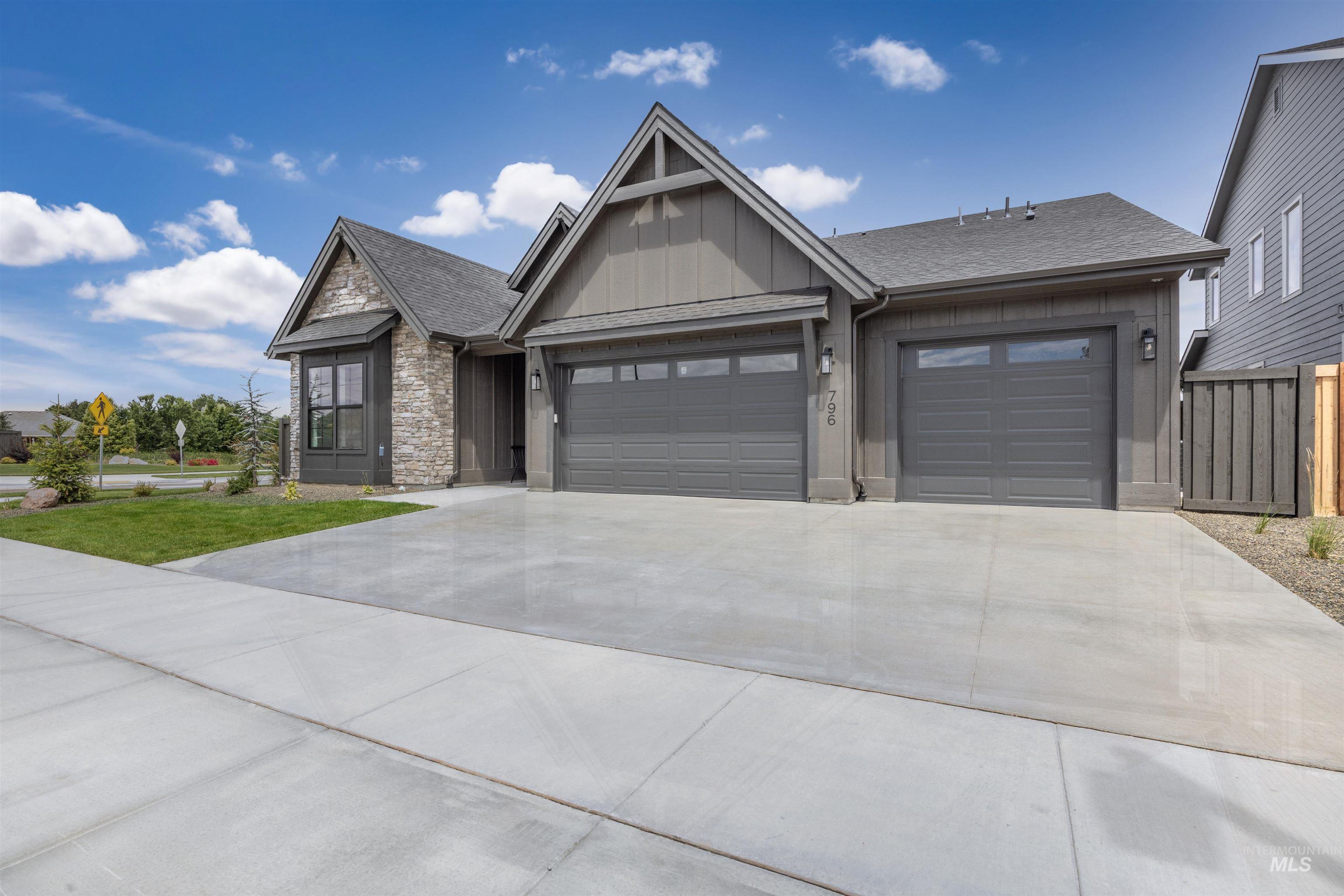 Contemporary exterior featuring board and batten siding with stone accents, a multi-car garage, concrete driveway, and a gabled roofline