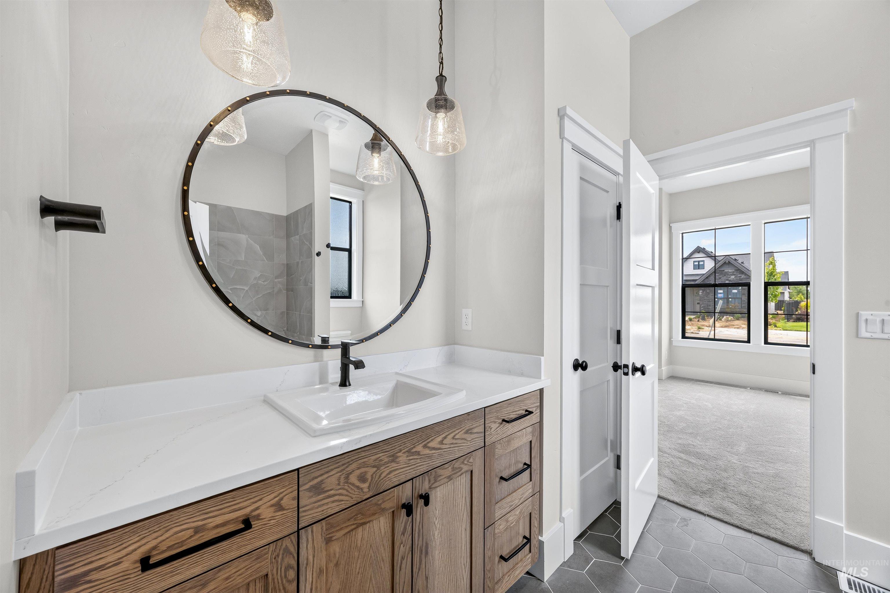 Bathroom vanity featuring a wood-finish cabinet with black hardware, white countertop, and rectangular undermount sink
