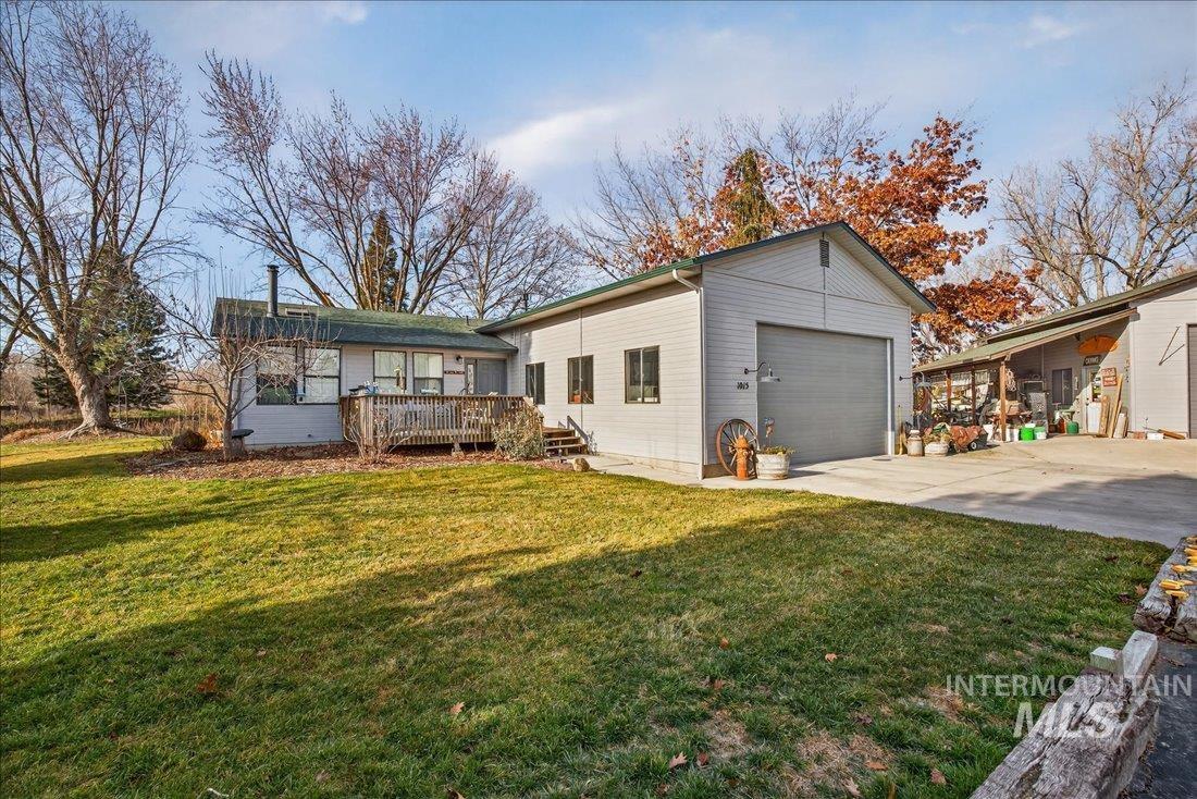 View of front of home with a front lawn, a wooden deck, driveway, and a garage