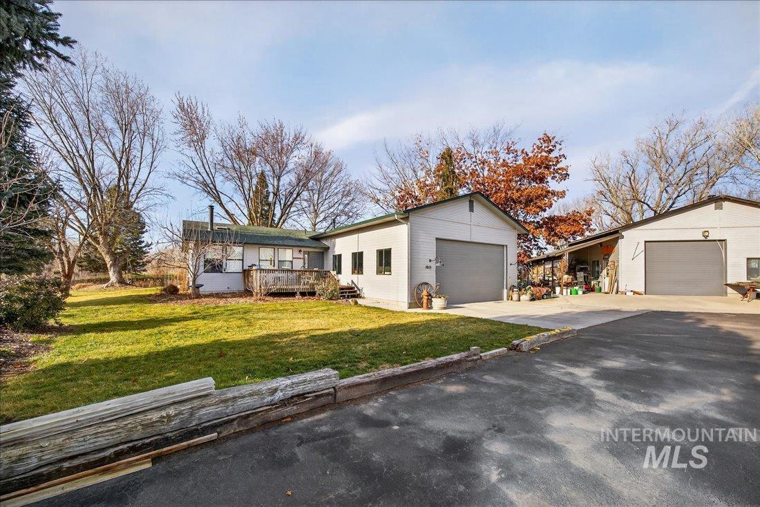 View of front of property with a deck, a front yard, and a garage