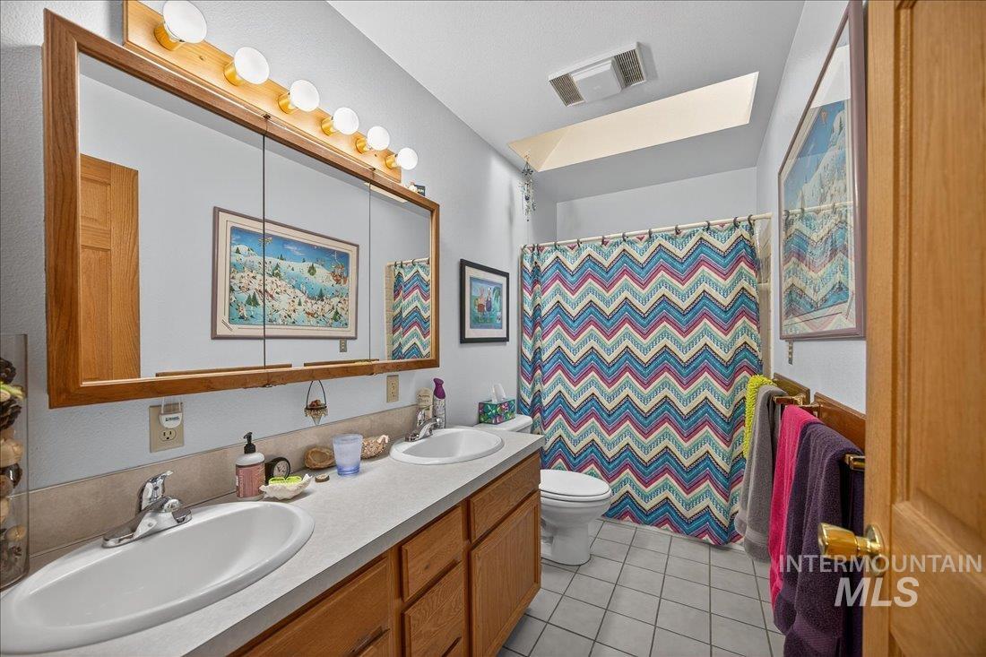 Bathroom featuring double vanity, a shower with curtain, and light tile patterned floors