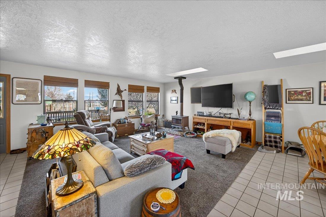 Living area with a textured ceiling, a wood stove, and light tile patterned floors