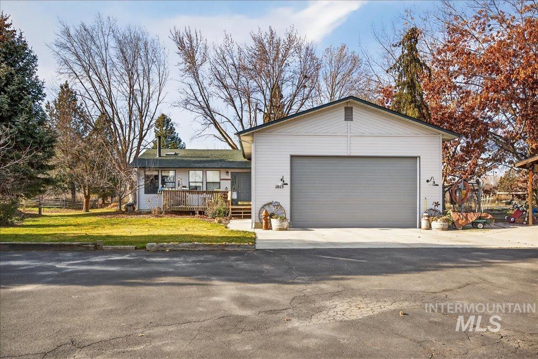View of front facade with a deck, concrete driveway, a front lawn, and an attached garage