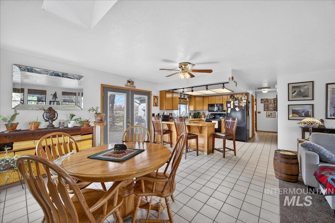 Dining space featuring light tile patterned floors, a ceiling fan, a textured ceiling, and french doors