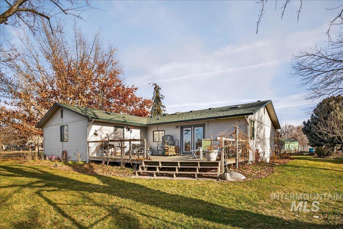 Rear view of property featuring a wooden deck and a yard