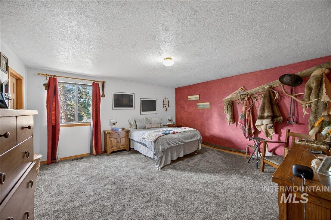 Carpeted bedroom with a textured ceiling and baseboards
