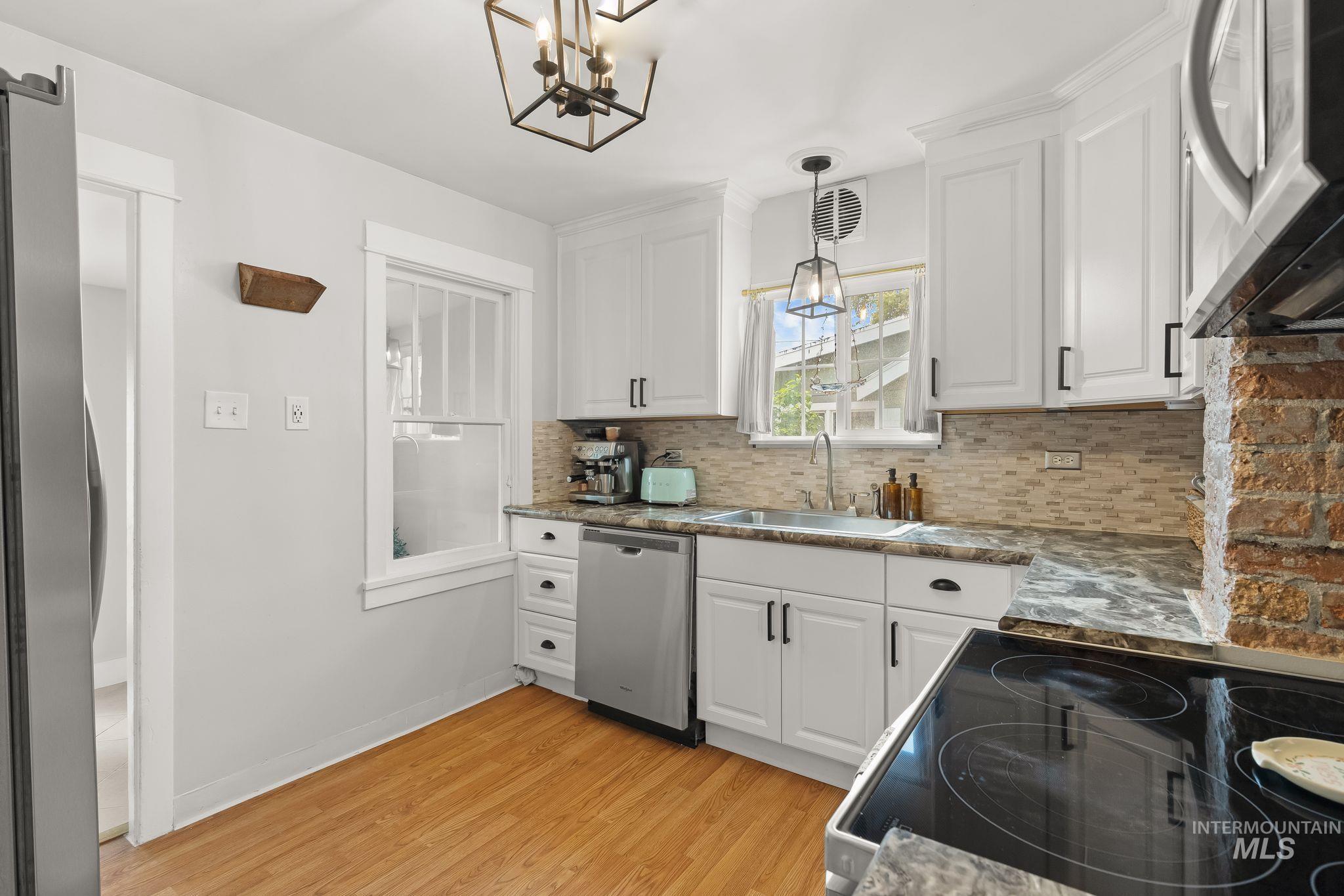 Kitchen featuring white cabinetry, a neutral tiled backsplash, and wood-finish flooring
