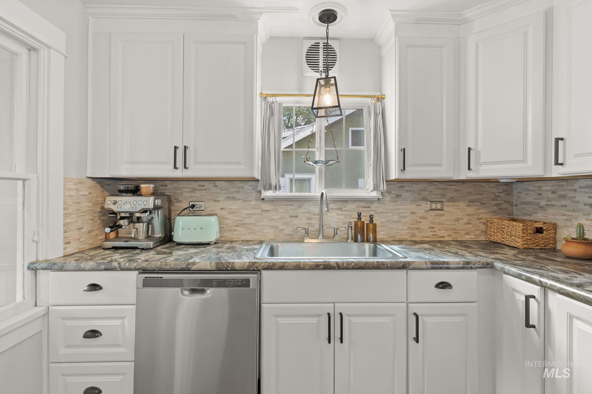 White shaker-style cabinetry with dark hardware, a mosaic tile backsplash, and a stainless steel sink with a gooseneck faucet