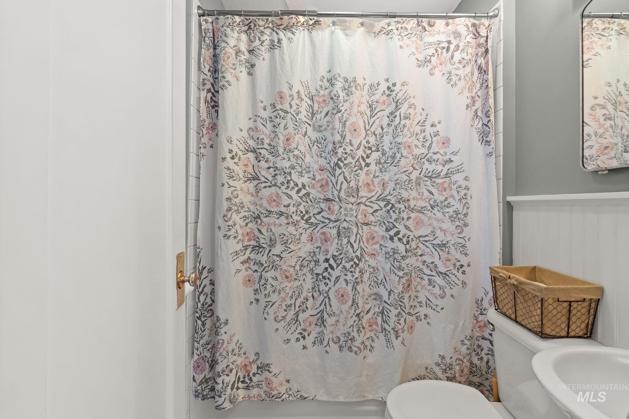 Bathroom featuring a white toilet, white wainscoting, and a wall-mounted mirror
