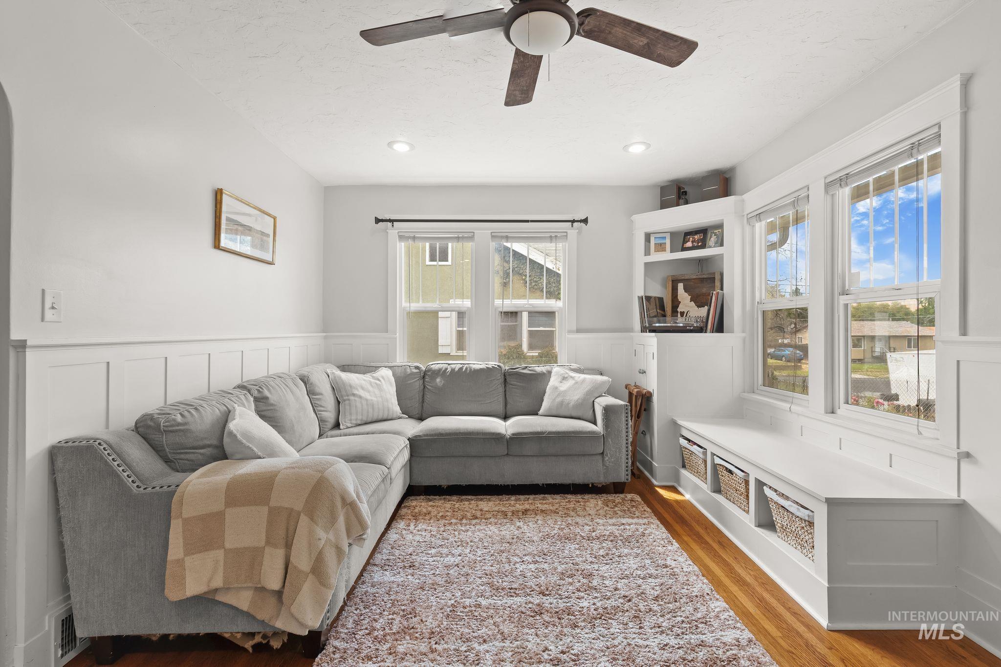 Living area featuring wood-finish flooring, white wainscoting, recessed lighting, and a ceiling fan