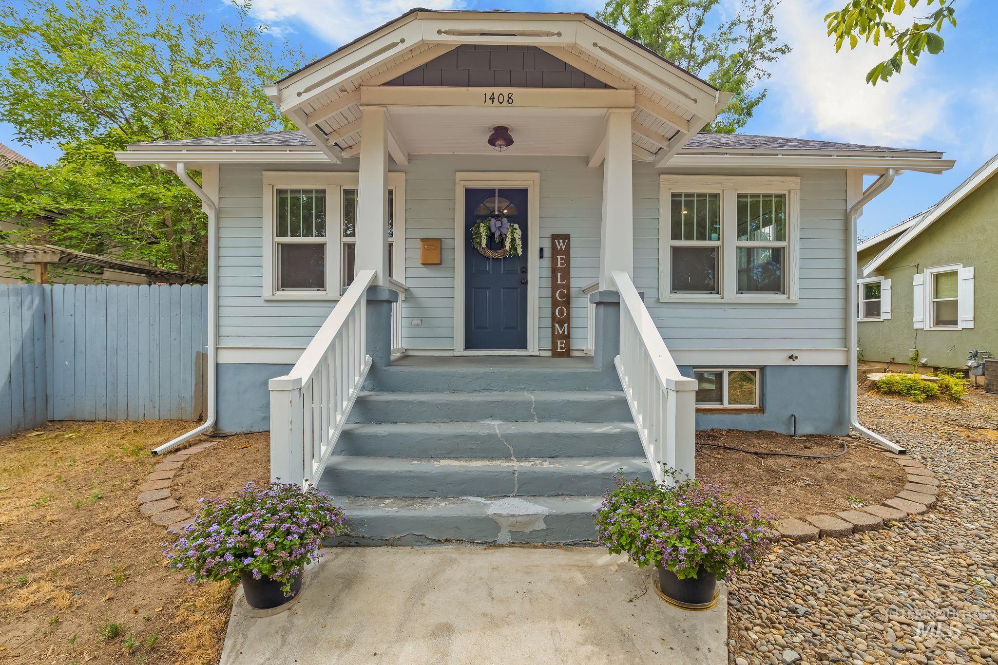 Light blue siding exterior featuring a covered entryway with white railings, a dark blue front door, and a decorative eave