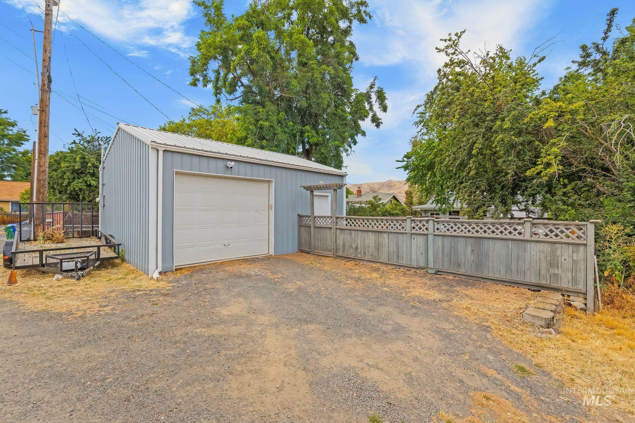 Detached metal-sided garage with a white roll-up door and a metal roof