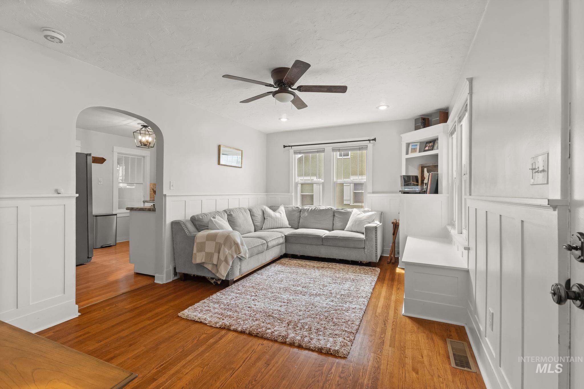 Living area with wood-finish flooring and white board and batten wall detailing