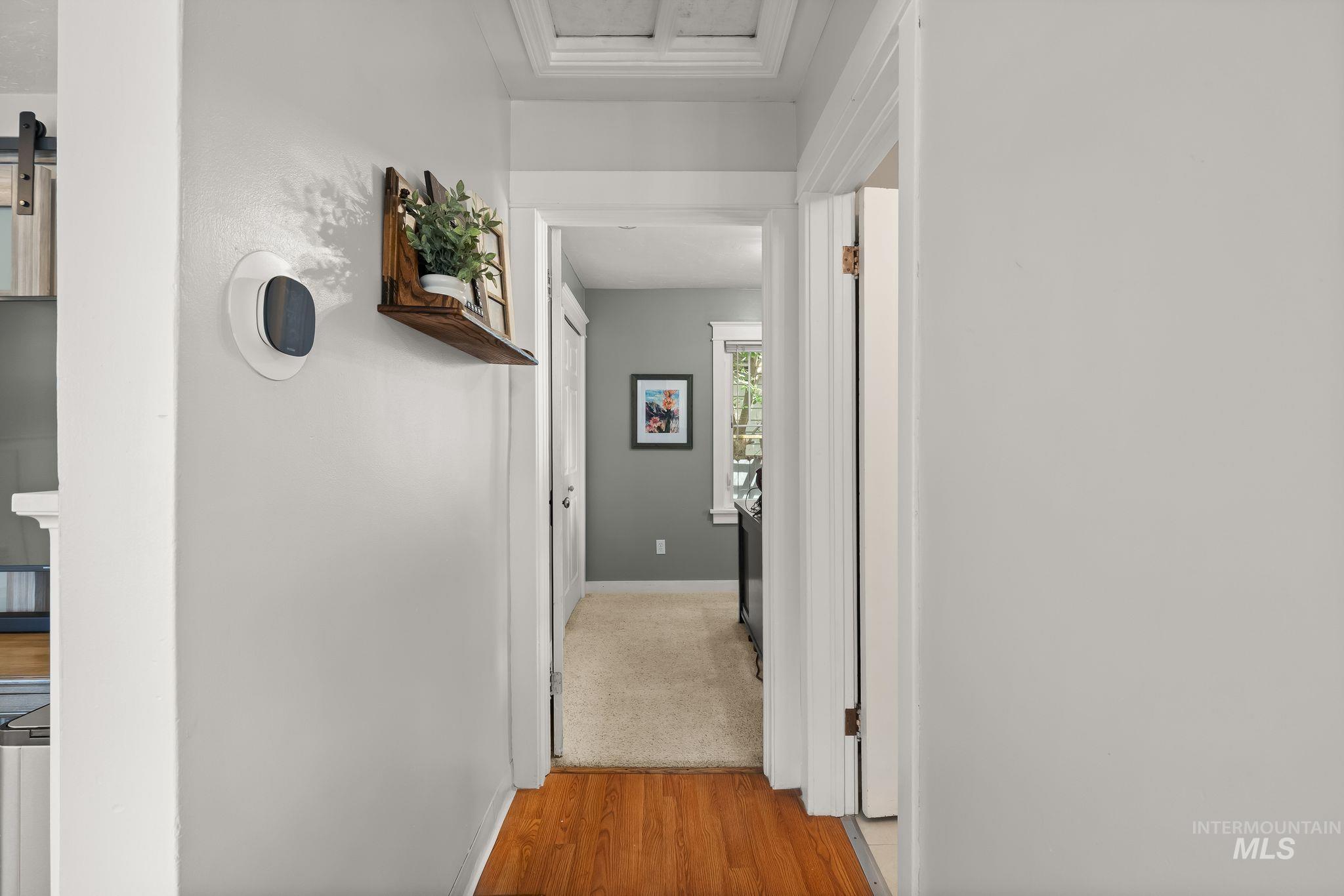Hallway featuring wood-finish flooring, light gray walls, and white trim