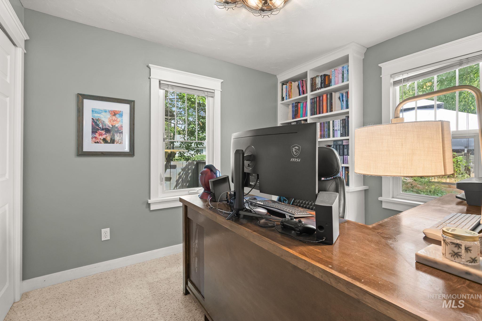 Built-in shelving, two windows, wall-to-wall carpeting, light gray wall paint, and overhead lighting