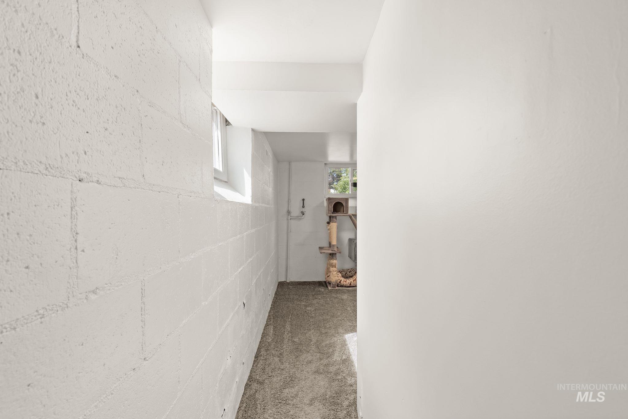 Brightly lit space featuring a painted block wall, concrete flooring, and a white interior door