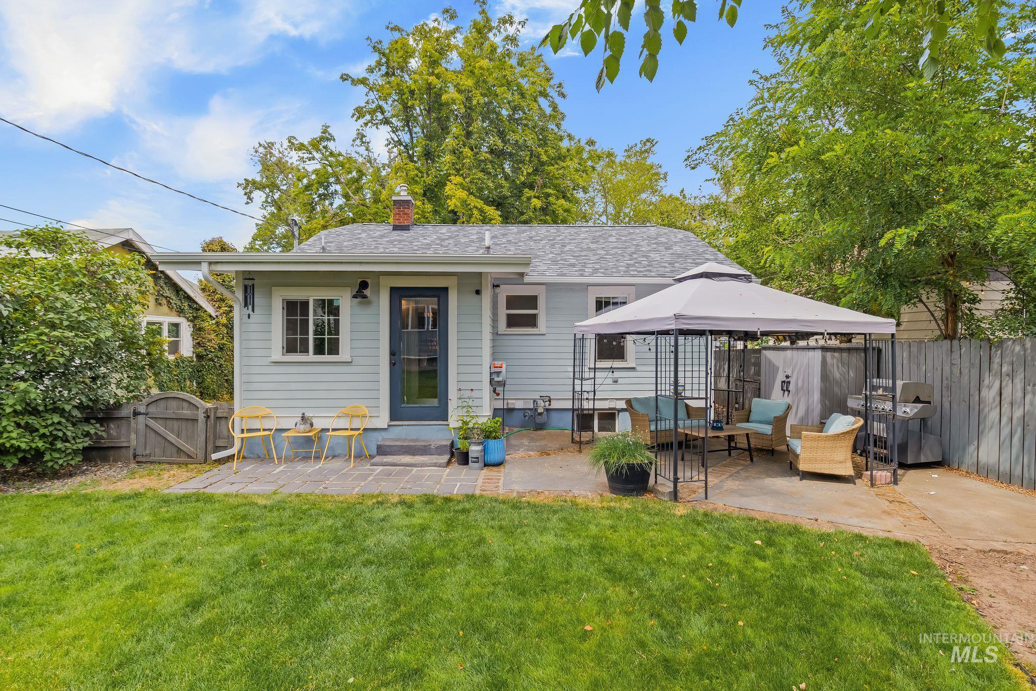 Expansive backyard featuring a green lawn, two distinct patio areas, and a private wooden fence