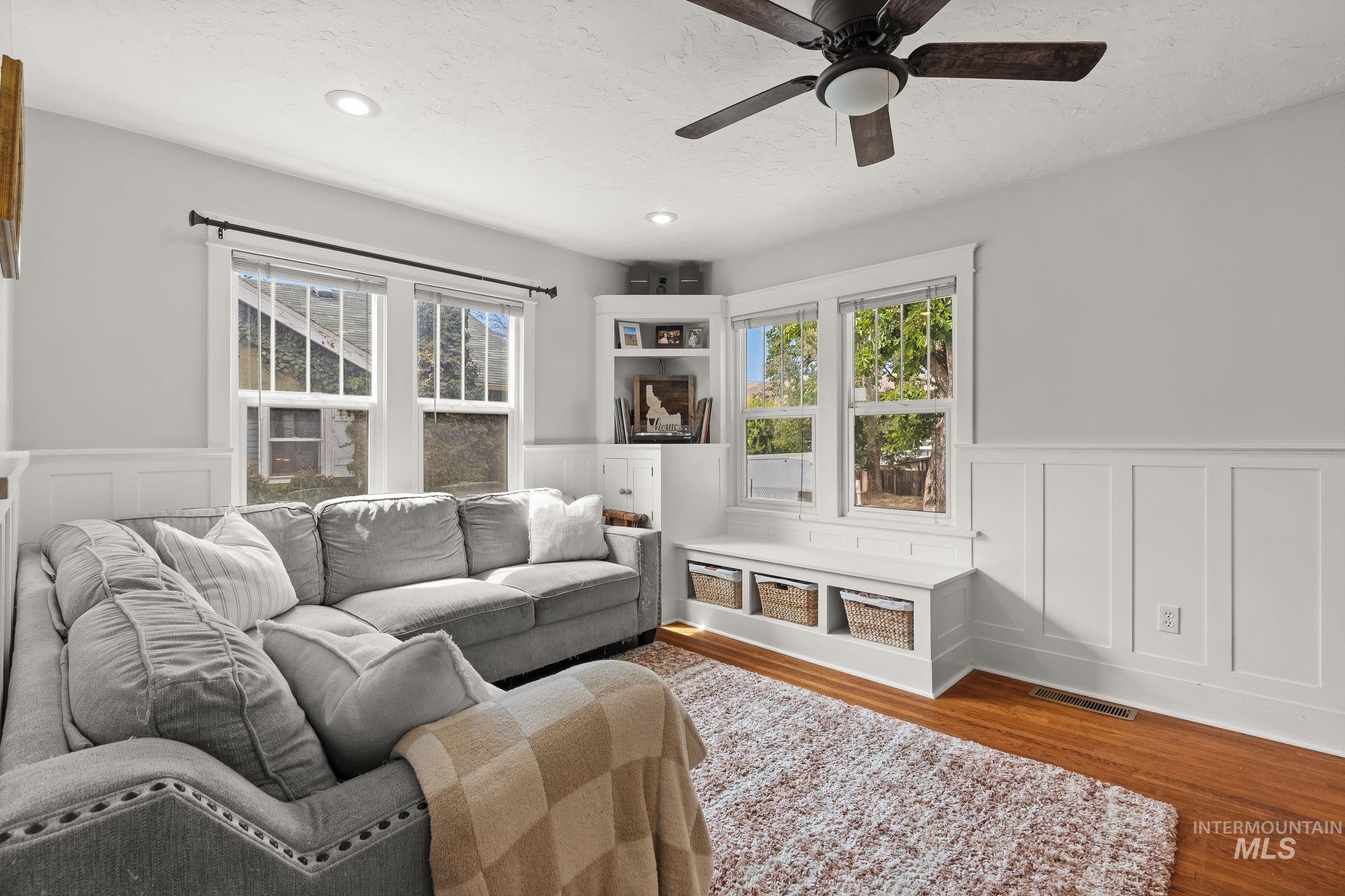 Living area featuring wood-finish flooring, white wainscoting, and recessed lighting